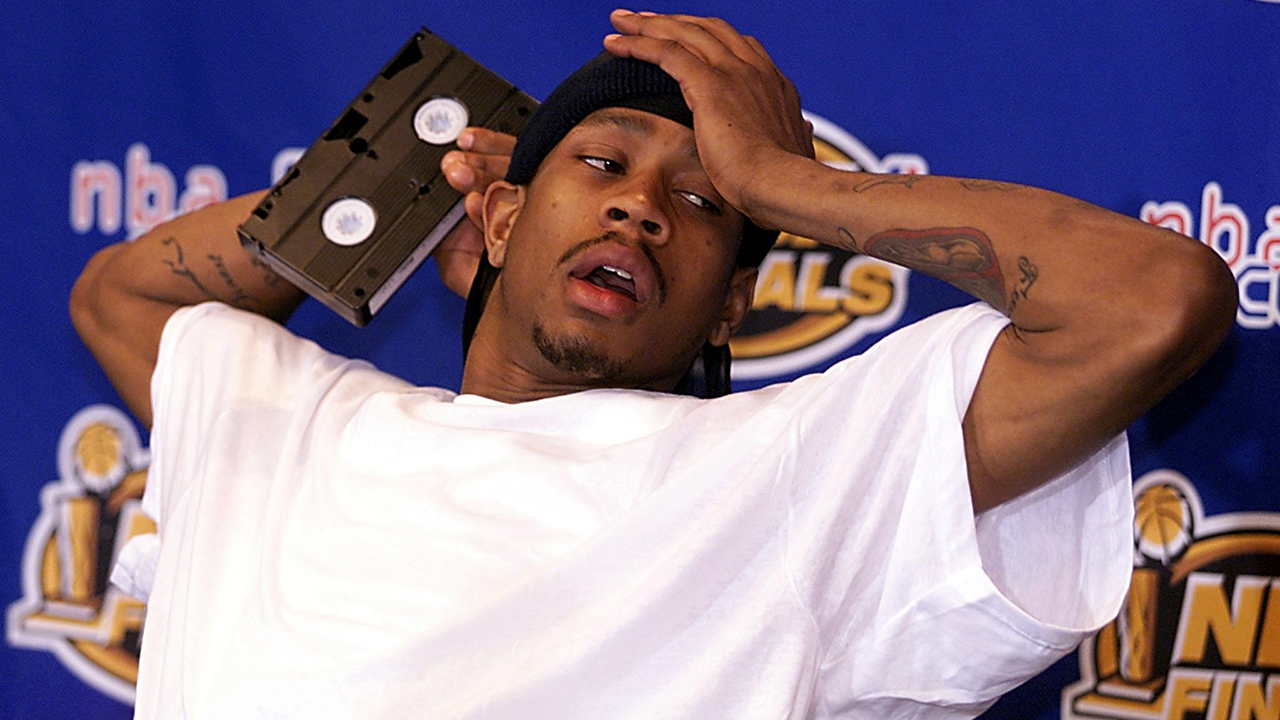 Allen Iverson at a press conference, holding a VHS cassette tape