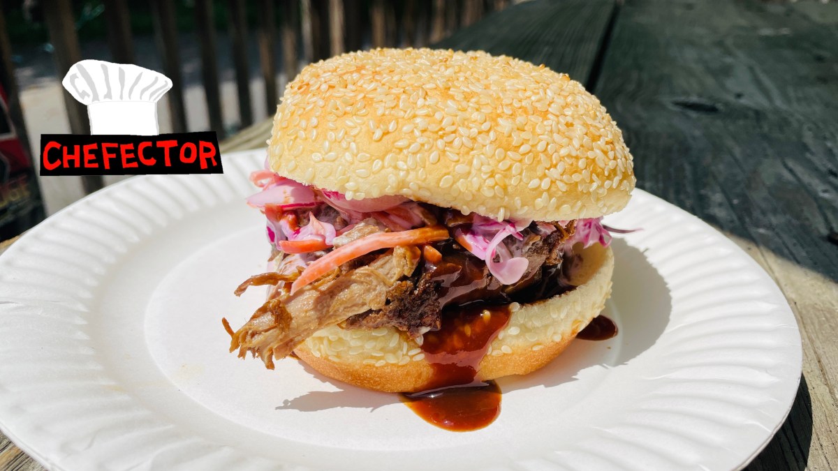 A pulled pork sandwich on a paper plate.