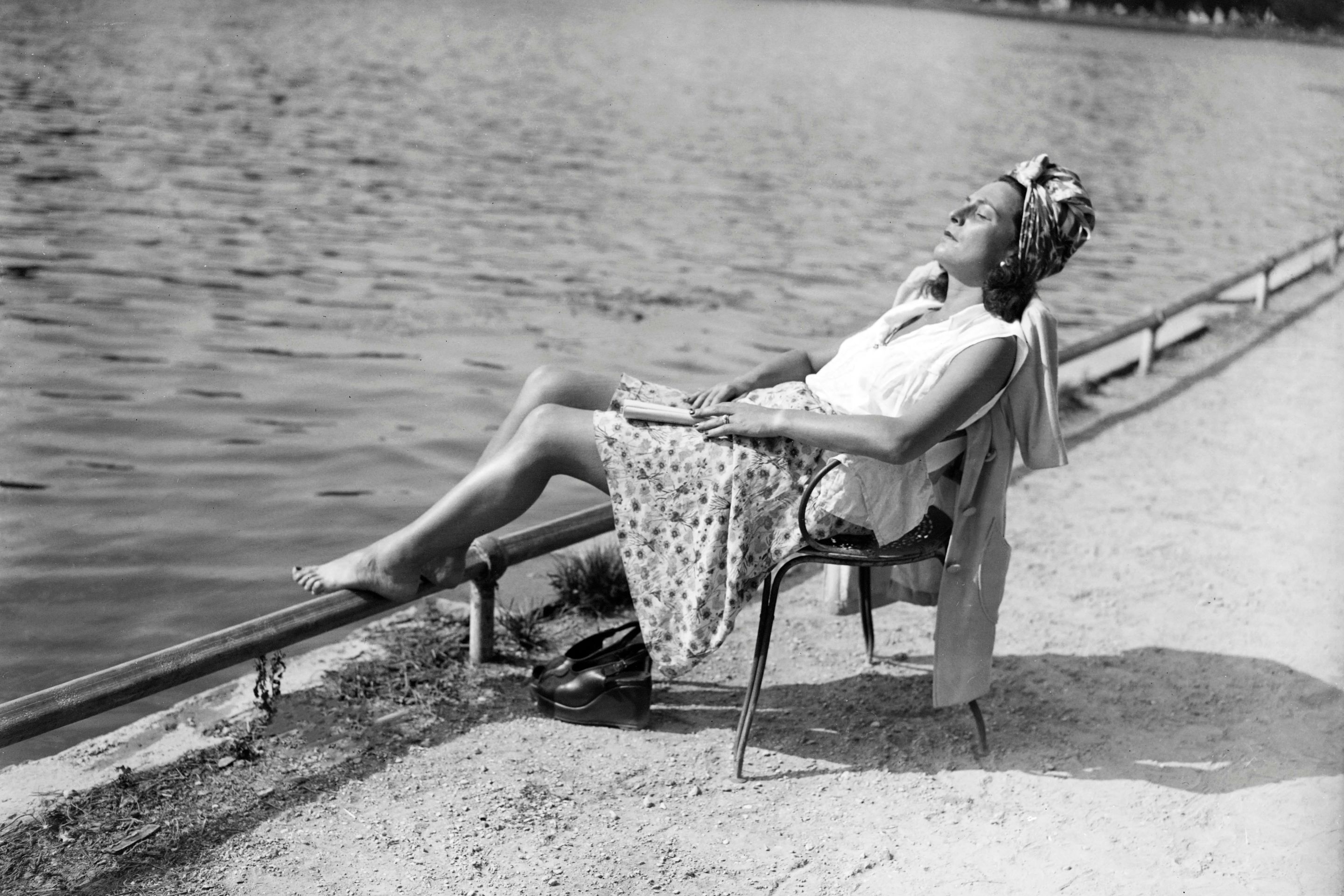 A woman rests and tans near a lake in the Bois de Boulogne near Paris, in June 1946, during a heat wave at the beginning of the 1946 summer.