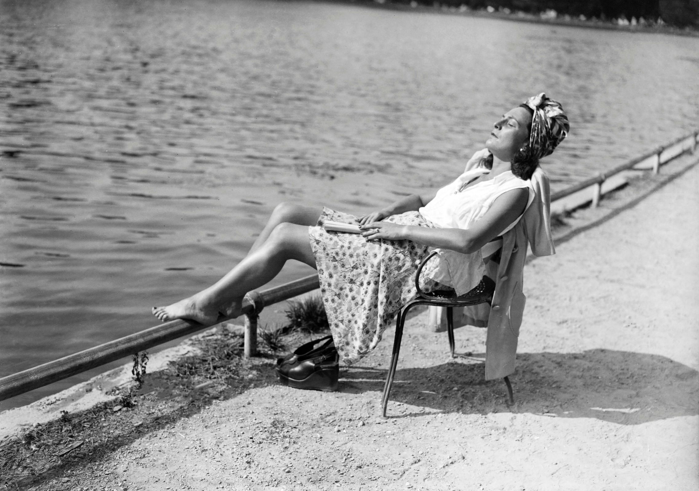 A woman rests and tans near a lake in the Bois de Boulogne near Paris, in June 1946, during a heat wave at the beginning of the 1946 summer.