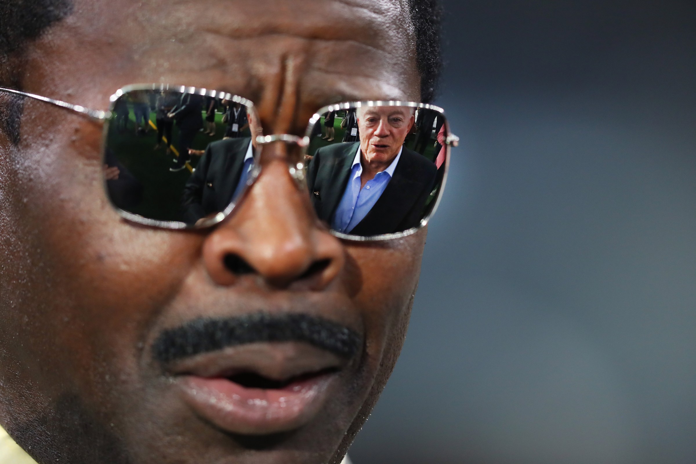 A photograph of Michael Irvin with the hideous image of Jerry Jones reflected in his sunglass lenses.