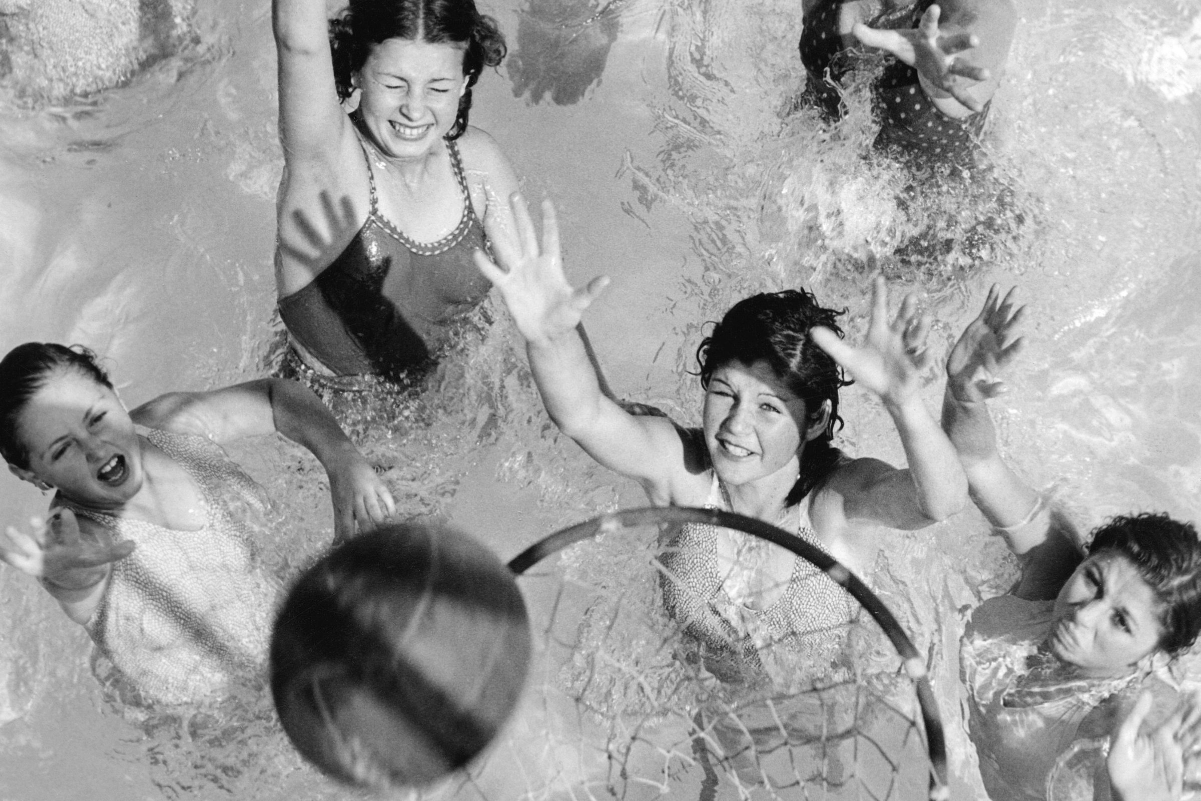 Young girls play basketball in a swimming pool in a 1930s photo