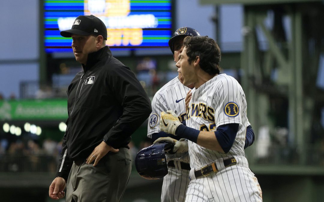 Christian Yelich #22 of the Milwaukee Brewers is held back by Quintin Berry #23 of the Milwaukee Brewers after being ejected from the game by umpire John Libka #84 during the sixth inning at American Family Field on July 10, 2021 in Milwaukee, Wisconsin.