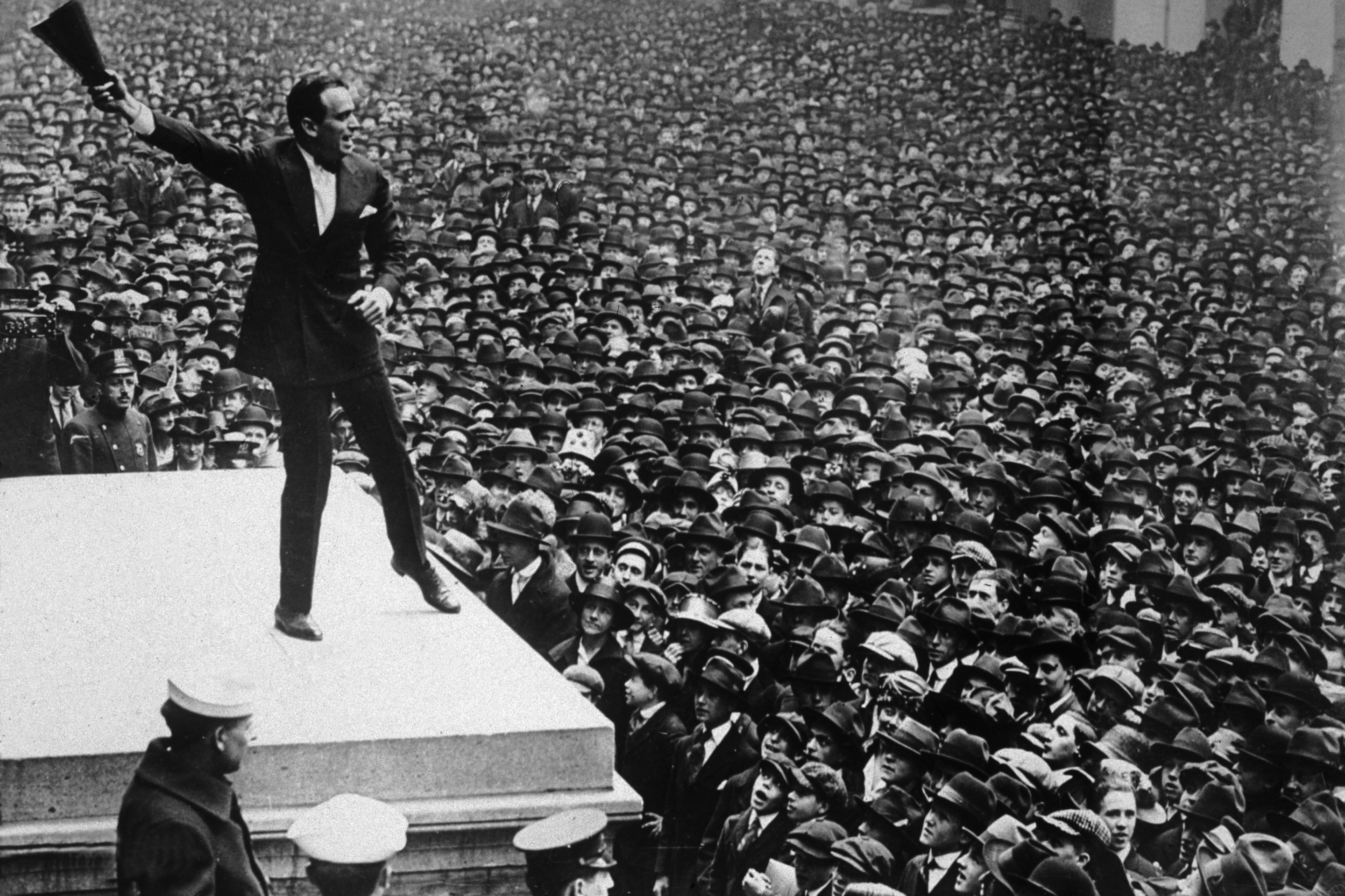 Full-length image of American actor Douglas Fairbanks Sr. waving a megaphone in the air while speaking from the Sub Treasury Building New York, to a sea of people, during a war bond rally, World War I.