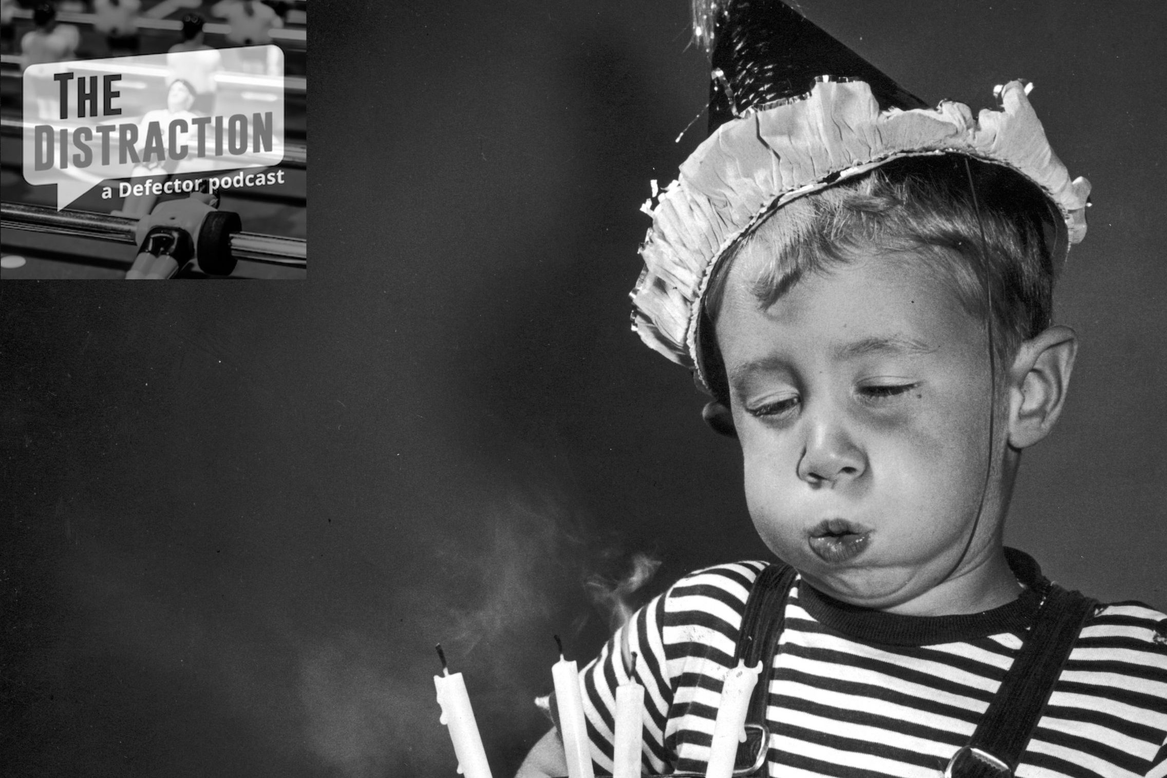 circa 1945: Studio image of a young boy wearing a party hat, blowing out the four candles on a chocolate birthday cake