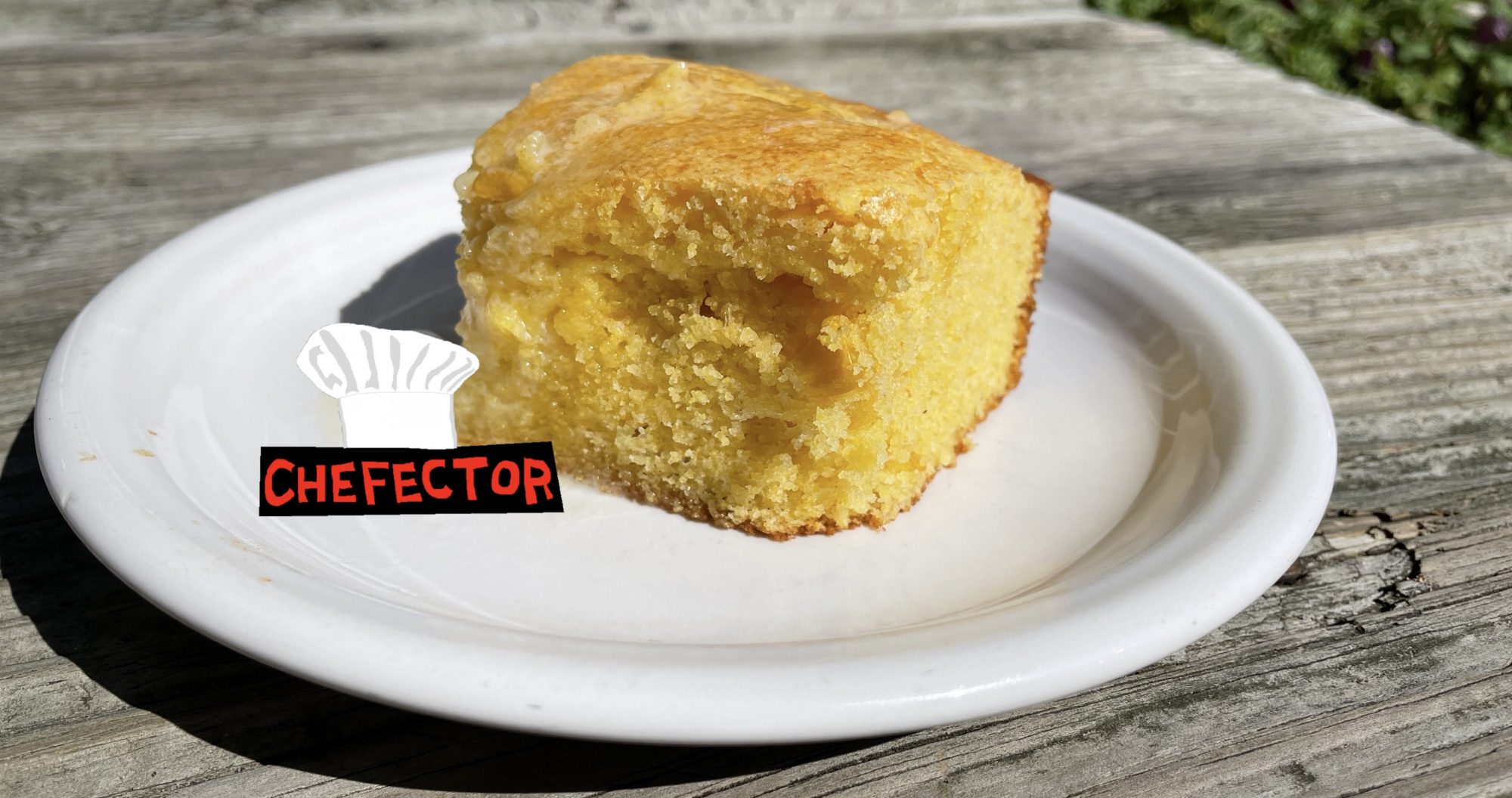 A hunk of cornbread on a plate on a rustic tabletop