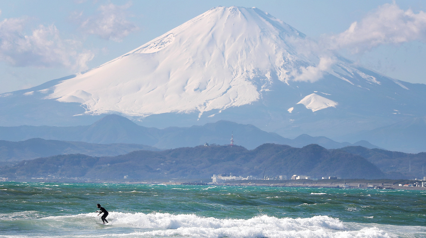 TOKYO, JAPAN - JANUARY 30: A local surfer is seen in action with Mount Fuji in the background from the beach of Enoshima during the build up to the Tokyo 2020 Olympic Games on January 30, 2020 in Fujisawa, Kanagawa Prefecture, Japan. The venue will hold the sailing events. (Photo by Clive Rose/Getty Images)