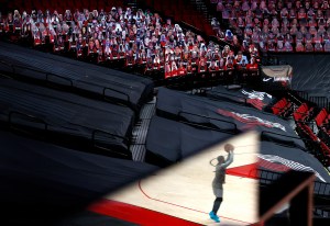 Damian Lillard's reflection, in front of rows of cardboard fans