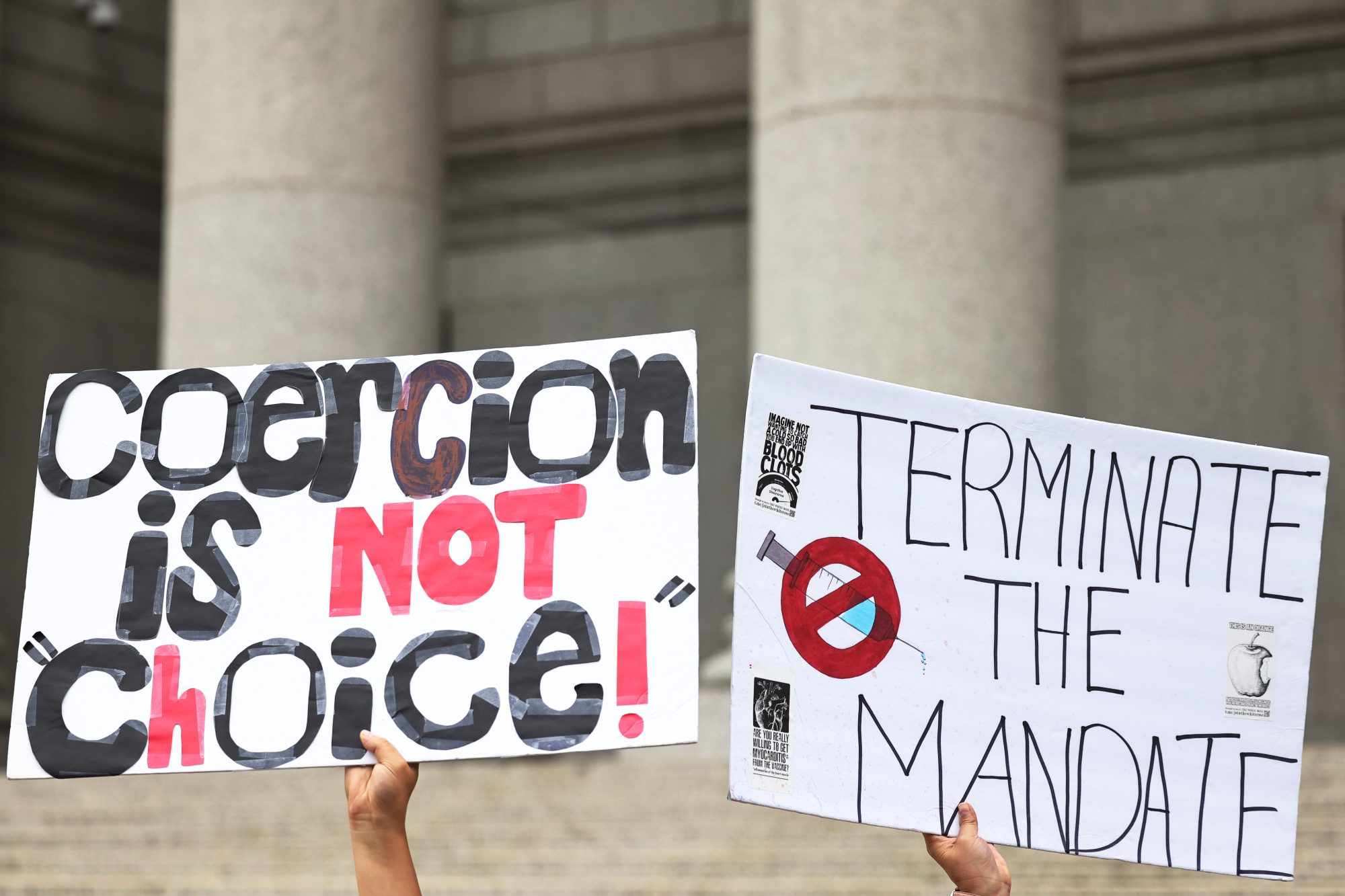 Protesters hold up signs opposing vaccine mandates.