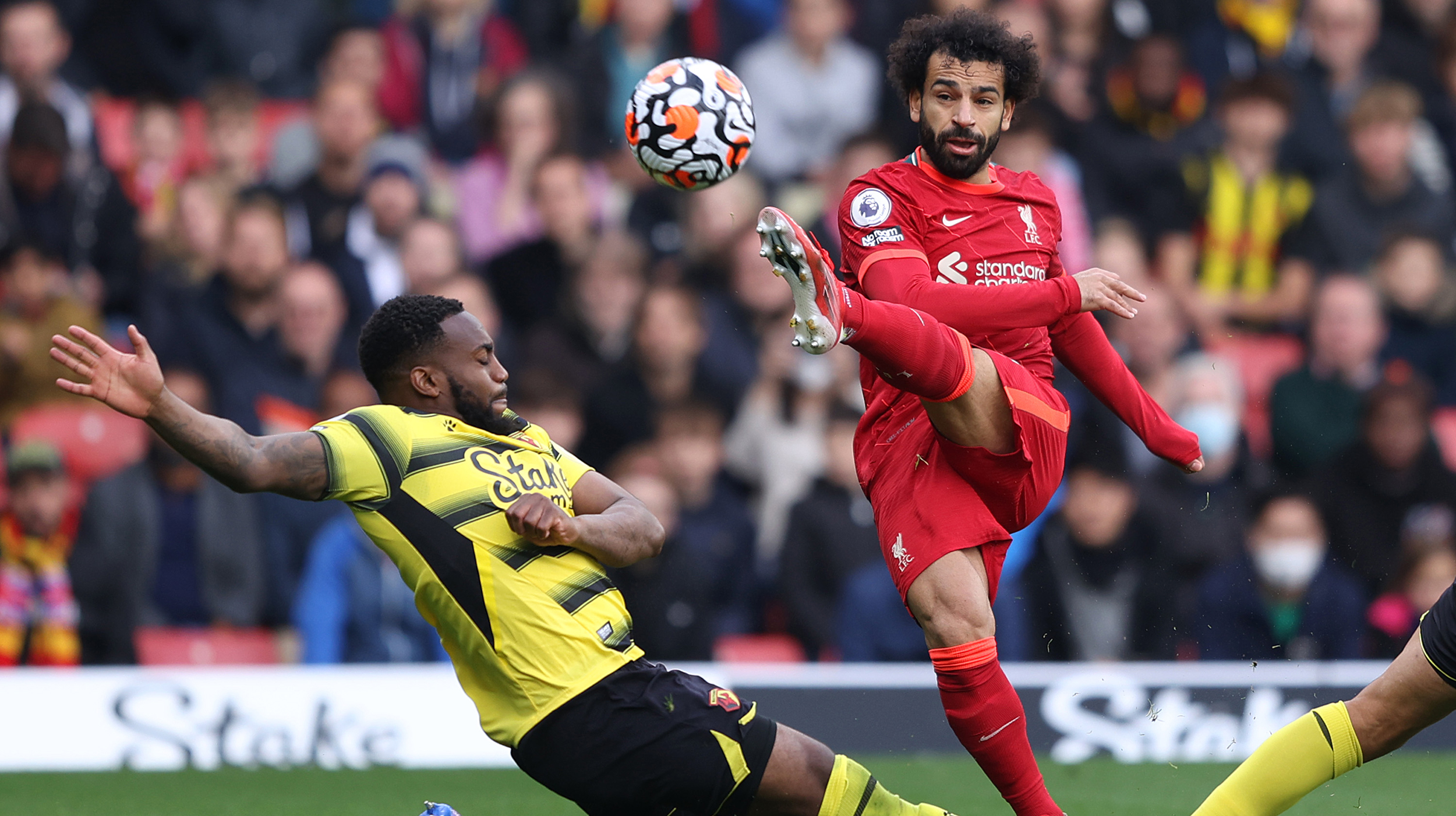 Mohamed Salah of Liverpool takes a shot as Danny Rose of Watford FC attempts to block during the Premier League match between Watford and Liverpool at Vicarage Road on October 16, 2021 in Watford, England.