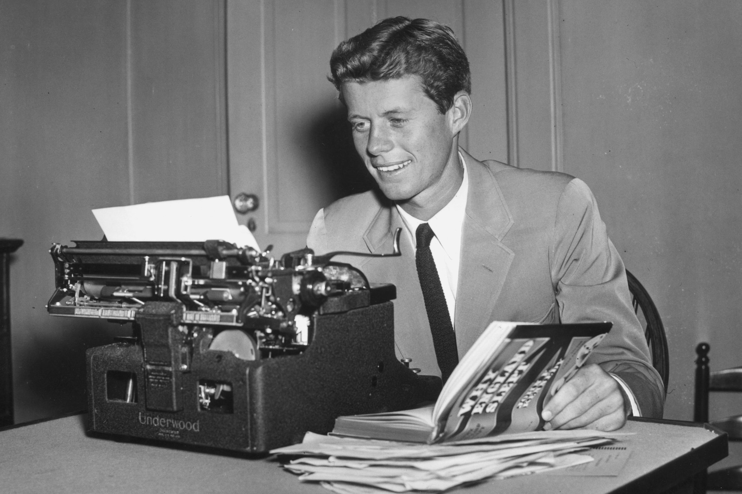 A young John F. Kennedy sits at a typewriter