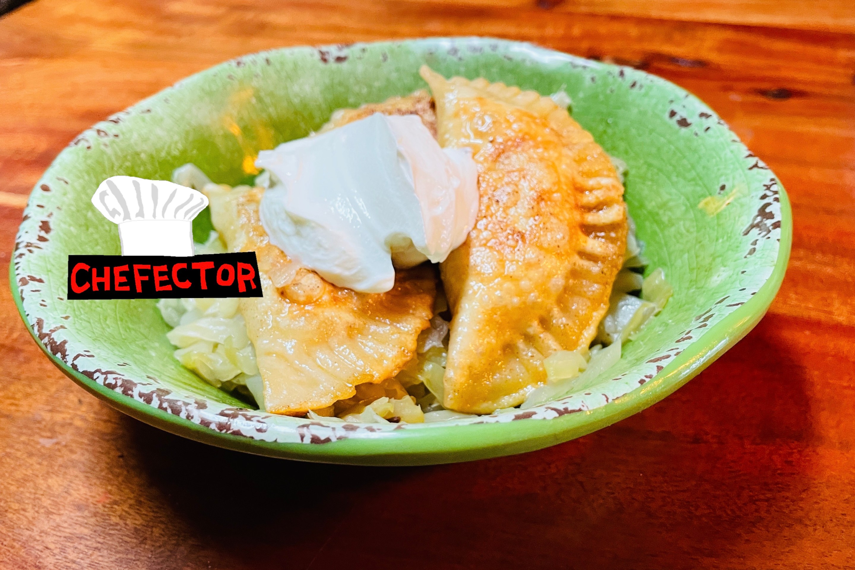 A bowl of pierogi with cabbage and sour cream