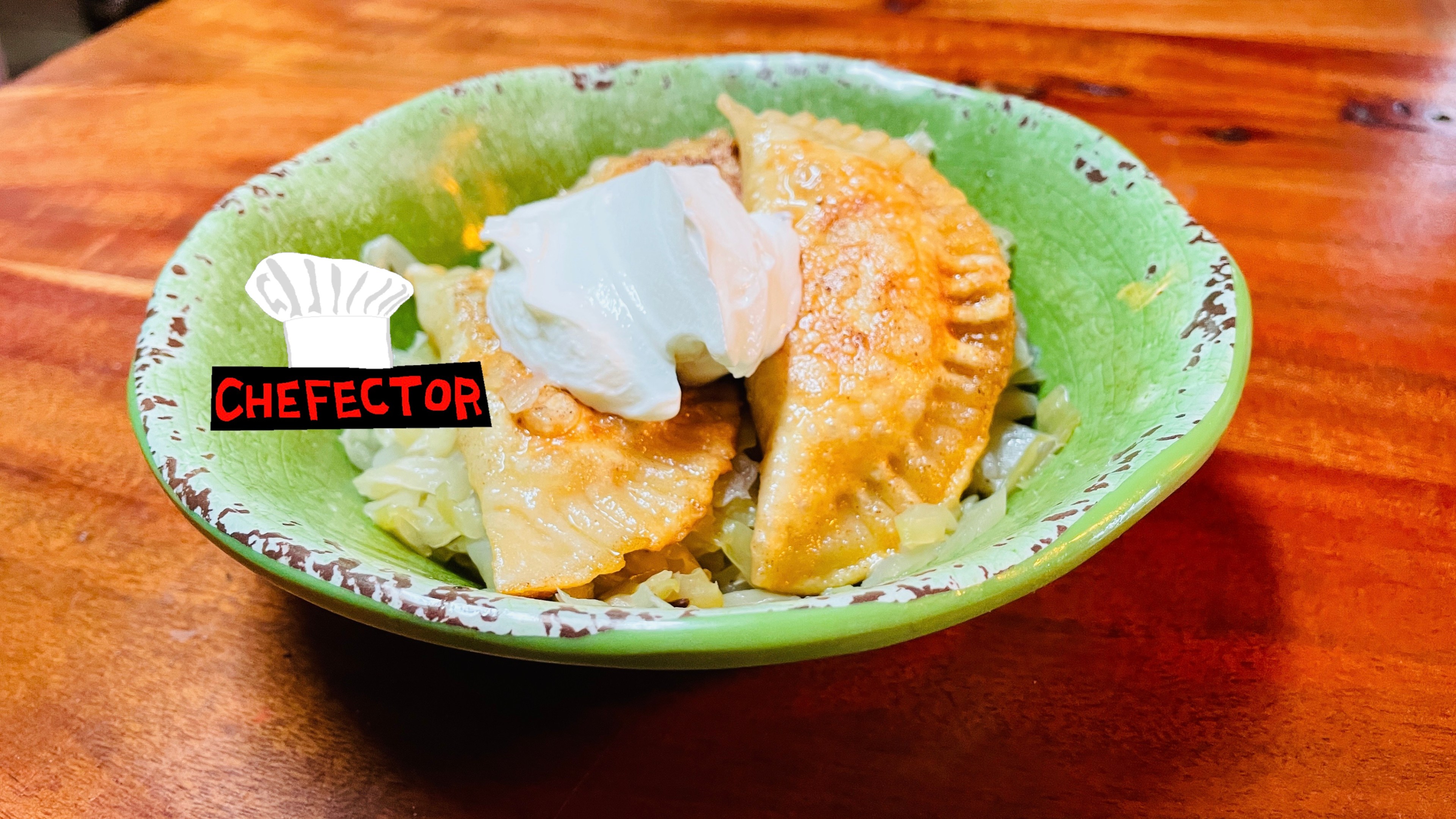 A bowl of pierogi with cabbage and sour cream