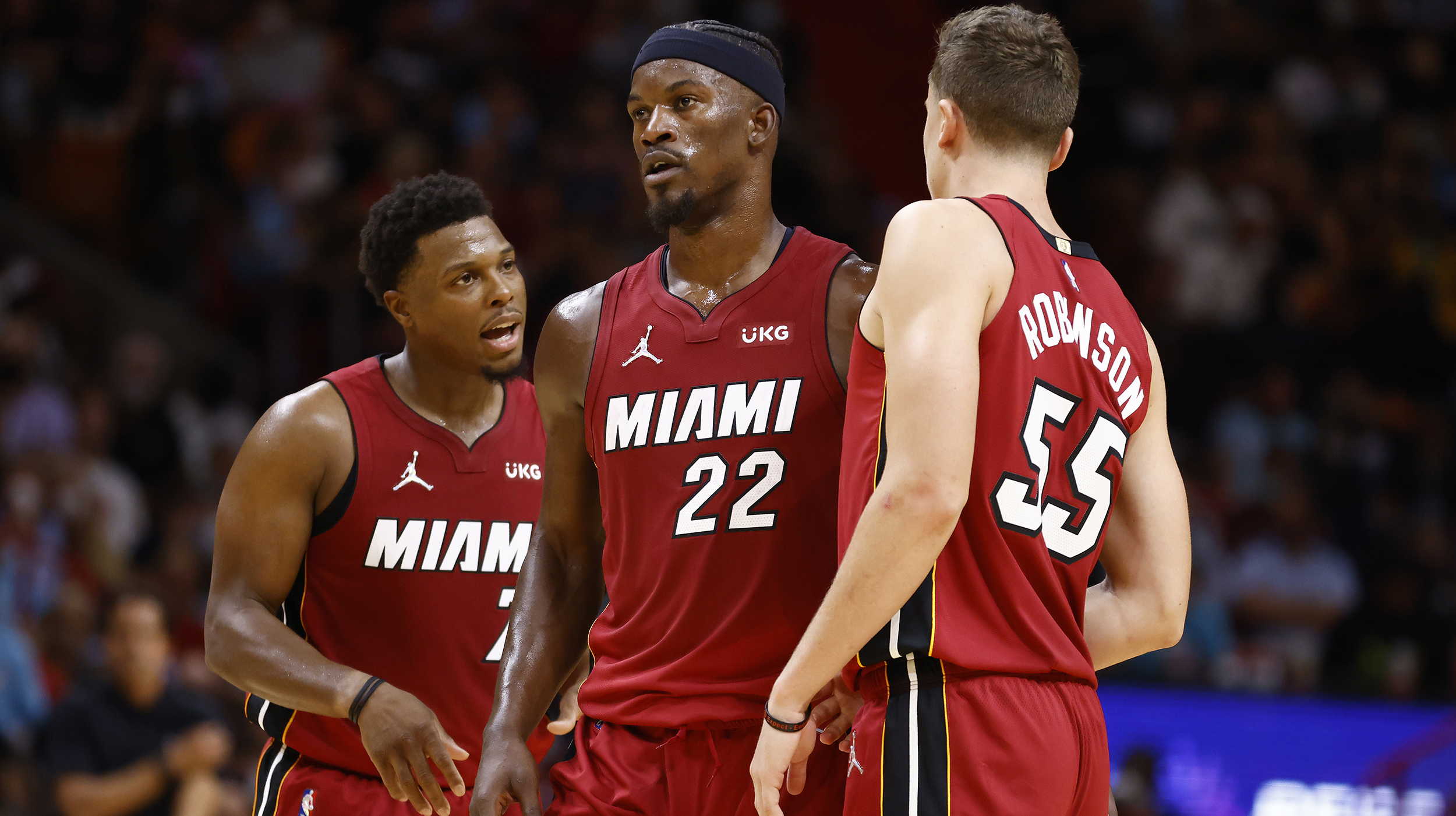 Kyle Lowry #7, Jimmy Butler #22, Duncan Robinson #55 of the Miami Heat look on against the Milwaukee Bucks at FTX Arena on October 21, 2021 in Miami, Florida.