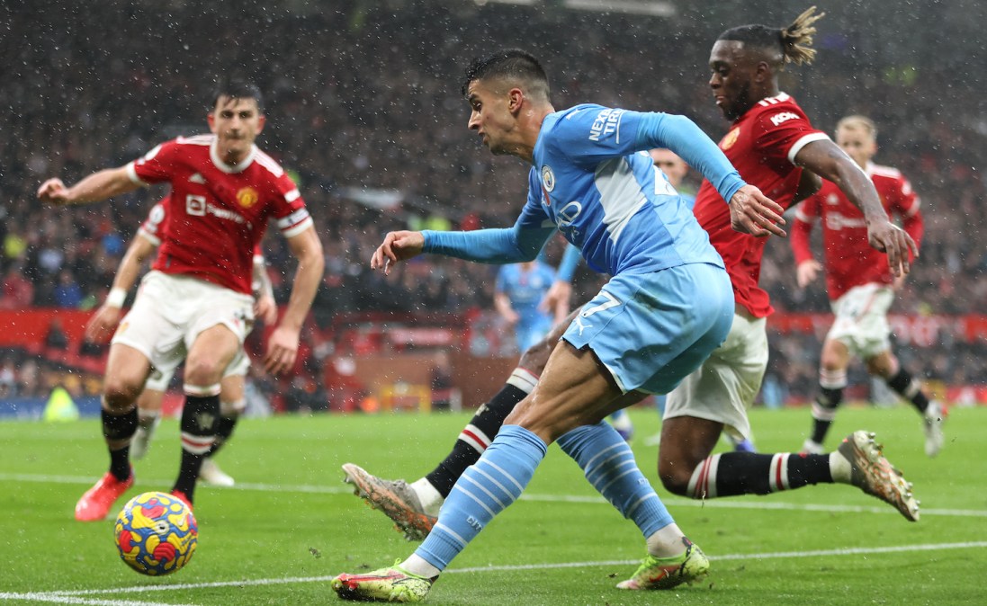 Joao Cancelo of Manchester City crosses the ball whilst under pressure from Aaron Wan-Bissaka of Manchester United during the Premier League match between Manchester United and Manchester City at Old Trafford on November 06, 2021 in Manchester, England.