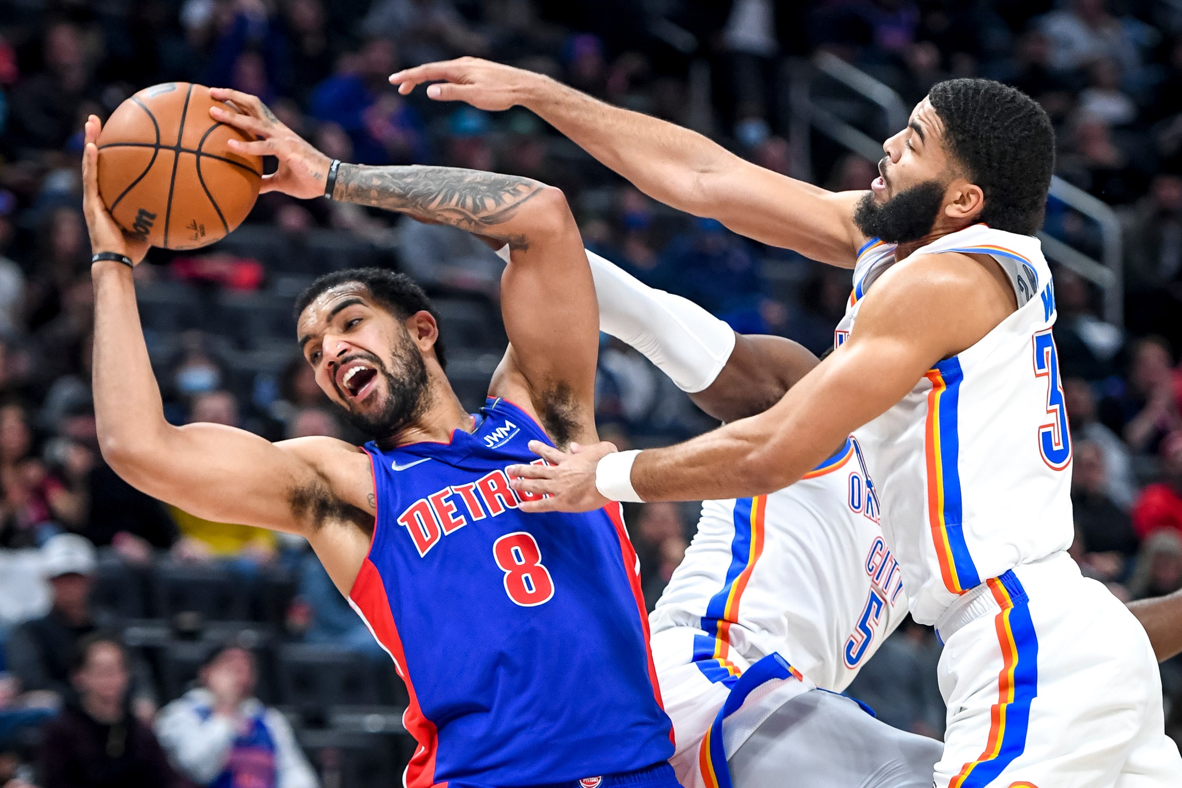 Trey Lyles #8 of the Detroit Pistons grabs a rebound against Luguentz Dort #5 and Kenrich Williams #34 of the Oklahoma City Thunder during the fourth quarter at Little Caesars Arena on December 06, 2021 in Detroit, Michigan.