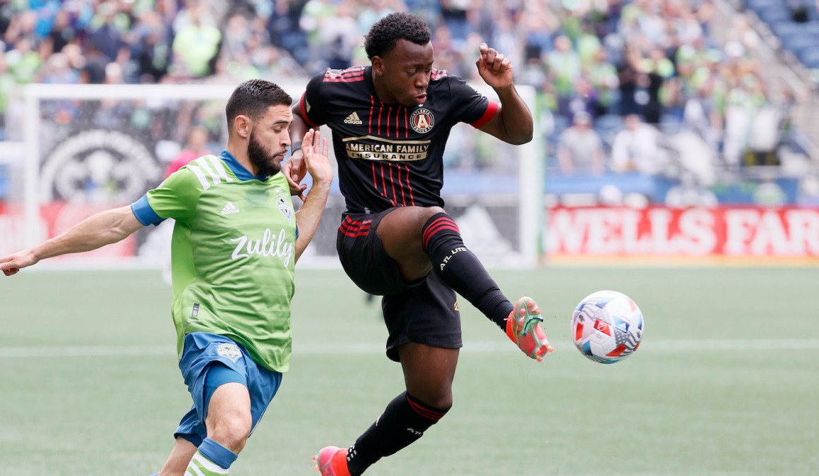 SEATTLE, WASHINGTON - MAY 23: George Bello #21 of Atlanta United against Alex Roldan #16 of Seattle Sounders during the first half at Lumen Field on May 23, 2021 in Seattle, Washington. (Photo by Steph Chambers/Getty Images)