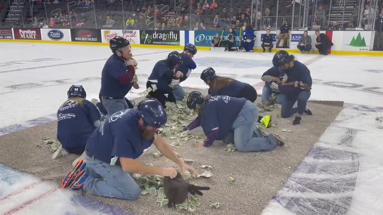 South Dakota teachers scrabble on a canvas for dollar bills during a hockey game