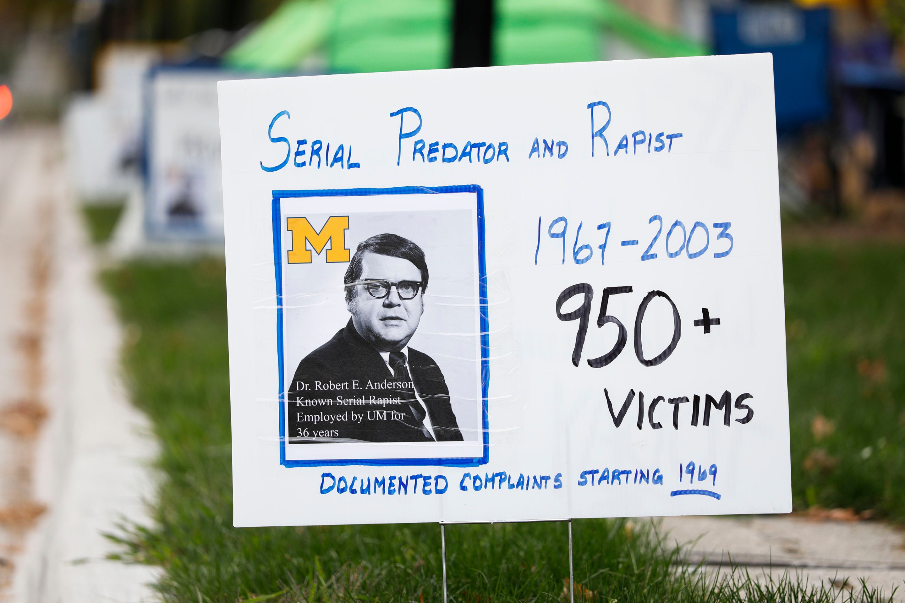 ANN ARBOR, MI - OCTOBER 13: A sign referring to former University of Michigan sports doctor Robert Anderson is on display at a vigil for survivors of sexual abuse in front of the home of outgoing UM President Mark Schlissel October 13, 2021 in Ann Arbor, Michigan. The group says it is standing in solidarity with sexual abuse victims of Anderson, U.S. Women's Gymnastics team doctor Larry Nassar, actor Bill Cosby and others.