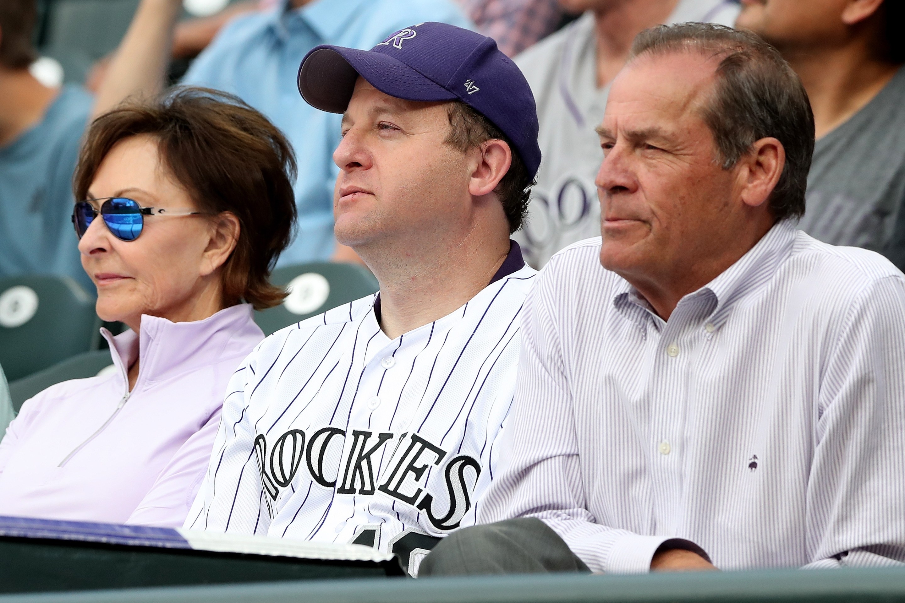 Colorado Governor Jared Polis, dressed like a child, sits with Rockies owner Dick Monfort at a home game in June 2021.