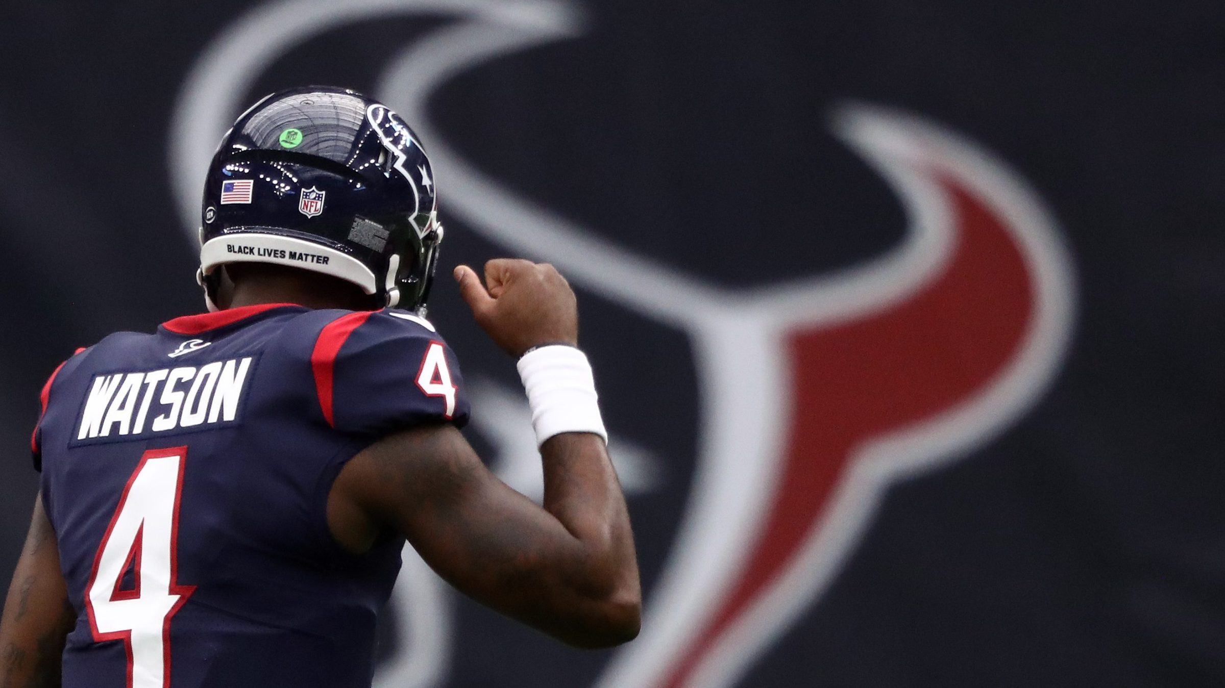 Deshaun Watson #4 of the Houston Texans celebrates a 30-14 win against the Jacksonville Jaguars at NRG Stadium on October 11, 2020 in Houston, Texas. His back is to the camera. What you see are his name across the back of his jersey and a giant Texans logo.