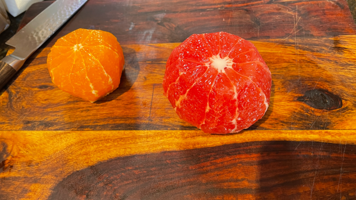 An orange and a grapefruit with their peels completely removed.