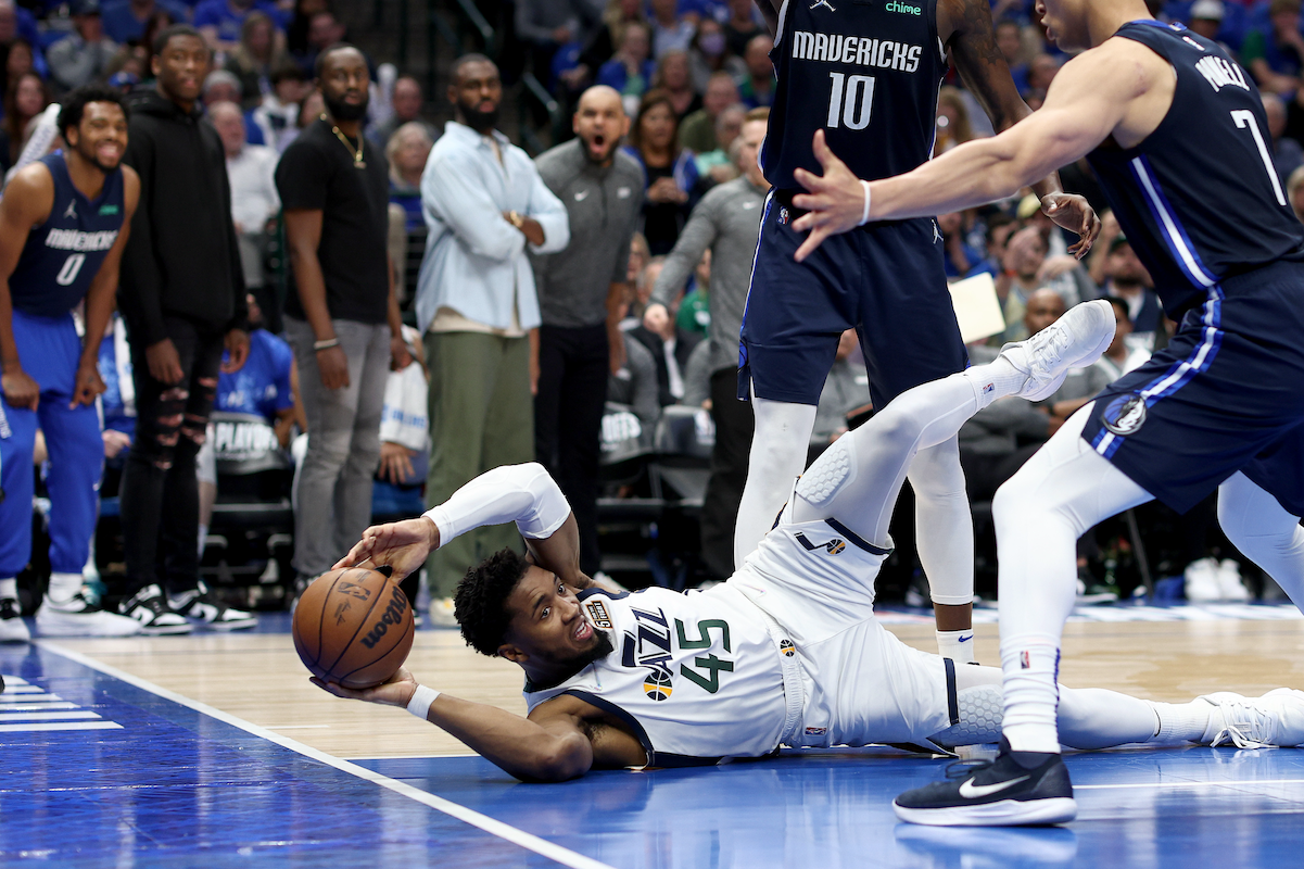 Donovan Mitchell of the Utah Jazz tries to pass the ball while laid out on the floor against the Dallas Mavericks
