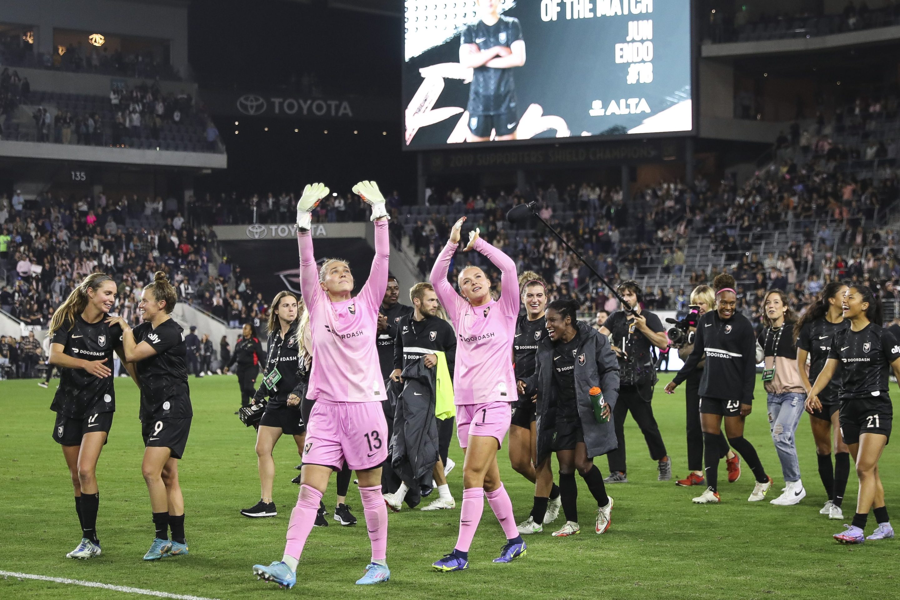 Goalkeepers DiDi Haracic #13 and Brittany Isenhour #1 of Angel City FC wave to fans after defeating North Carolina Courage at Banc of California Stadium on April 29, 2022 in Los Angeles, California.