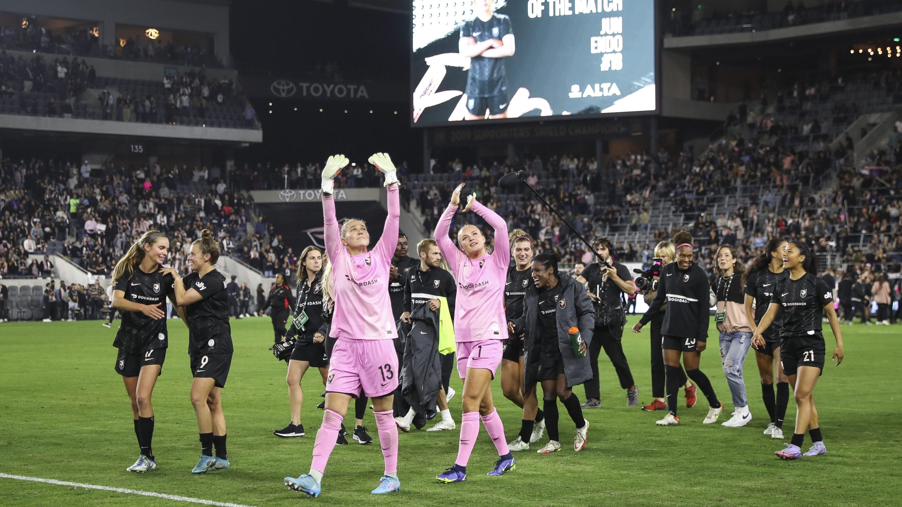 Goalkeepers DiDi Haracic #13 and Brittany Isenhour #1 of Angel City FC wave to fans after defeating North Carolina Courage at Banc of California Stadium on April 29, 2022 in Los Angeles, California.