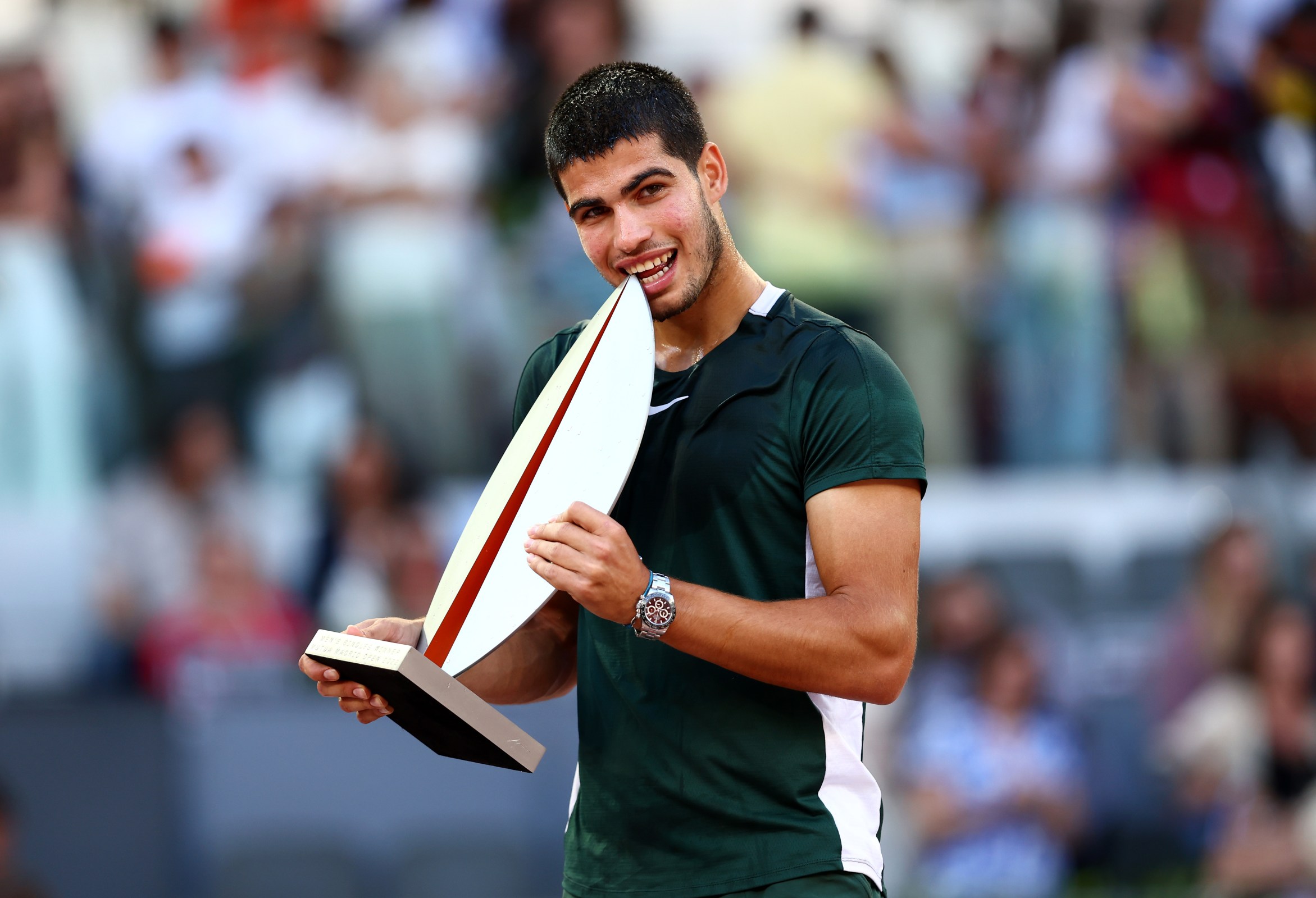 Carlos Alcaraz bites his Madrid Open trophy.