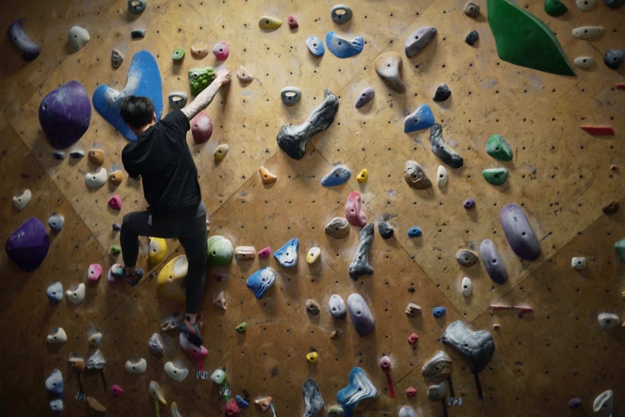 A climber scales a climbing wall at Brooklyn Boulders
