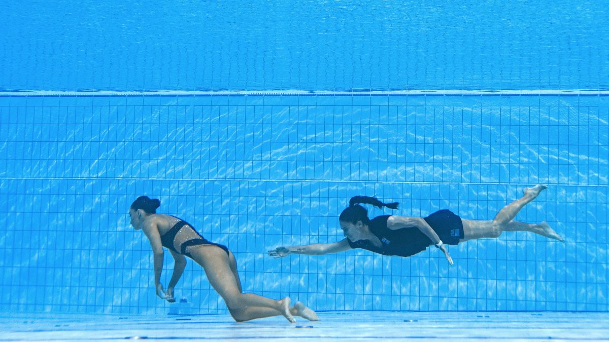 TOPSHOT - A member of Team USA (R) swims to recover USA's Anita Alvarez (L), from the bottom of the pool during an incident in the women's solo free artistic swimming finals, during the Budapest 2022 World Aquatics Championships at the Alfred Hajos Swimming Complex in Budapest on June 22, 2022. (Photo by Oli SCARFF / AFP)
