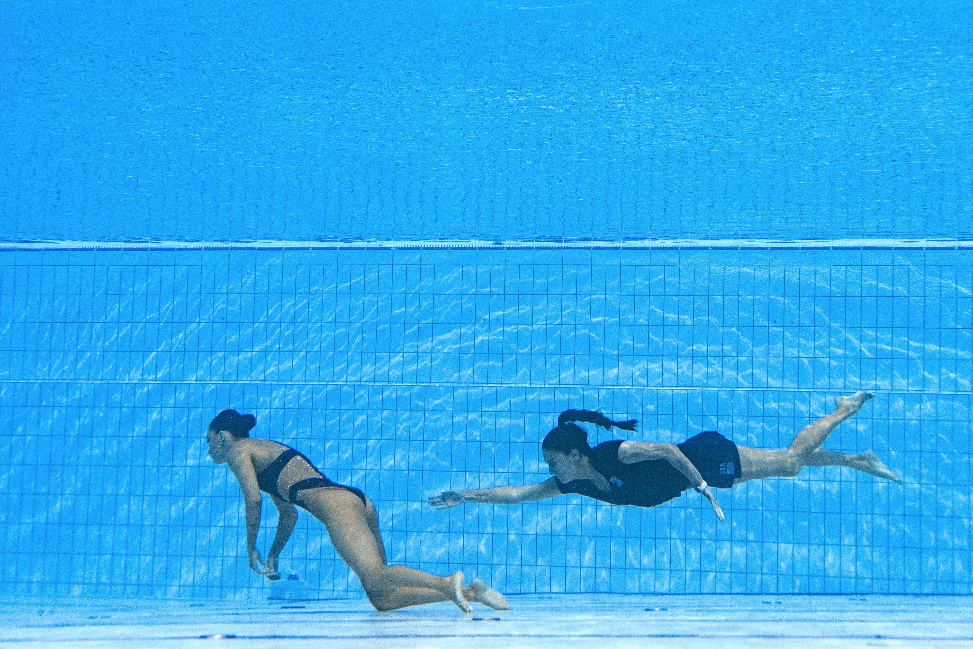 TOPSHOT - A member of Team USA (R) swims to recover USA's Anita Alvarez (L), from the bottom of the pool during an incident in the women's solo free artistic swimming finals, during the Budapest 2022 World Aquatics Championships at the Alfred Hajos Swimming Complex in Budapest on June 22, 2022. (Photo by Oli SCARFF / AFP)