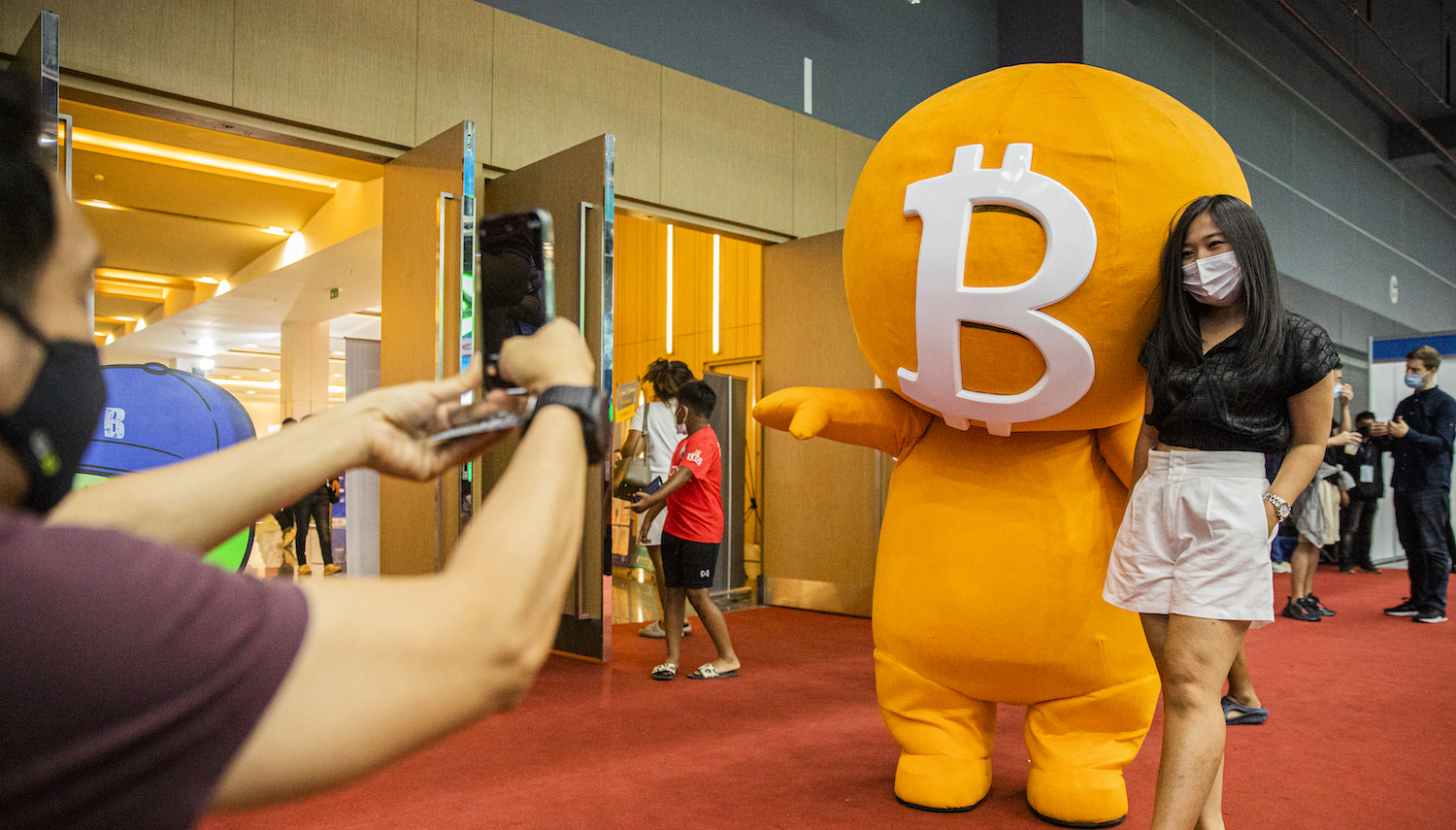 BANGKOK, THAILAND - MAY 14: A woman poses with a Bitcoin mascot during the Thailand Crypto Expo 2022 on May 14, 2022 in Bangkok, Thailand. Cryptocurrency Enthusiasts attend Thailand Crypto Expo 2022, the largest cryptocurrency exposition in Southeast Asia, at the Bangkok International Trade and Exhibition Center. Visitors learn about blockchain projects, exchanges, mining, NFT production, and gamefi technology. The exposition comes during a global market crash. (Photo by Lauren DeCicca/Getty Images)
