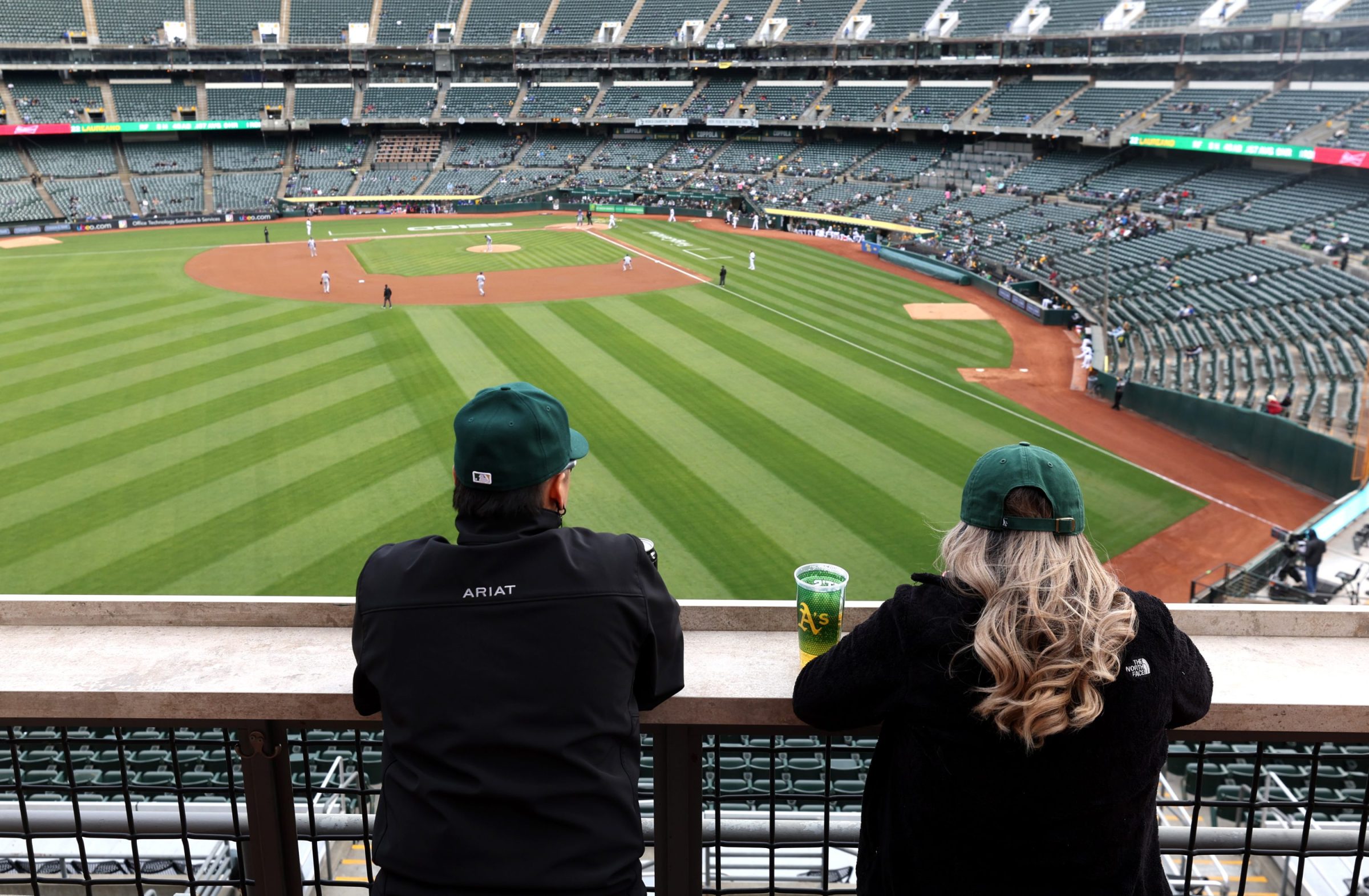 Two baseball fans watch the Oakland Athletics play the Texas Rangers
