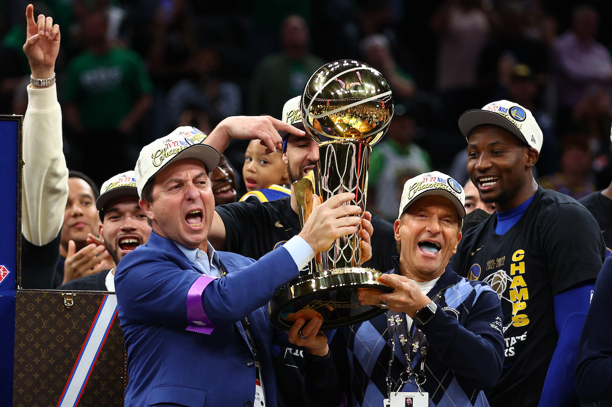 Warriors owners Joe Lacob and Peter Guber hoist the Larry O'Brien NBA championship trophy