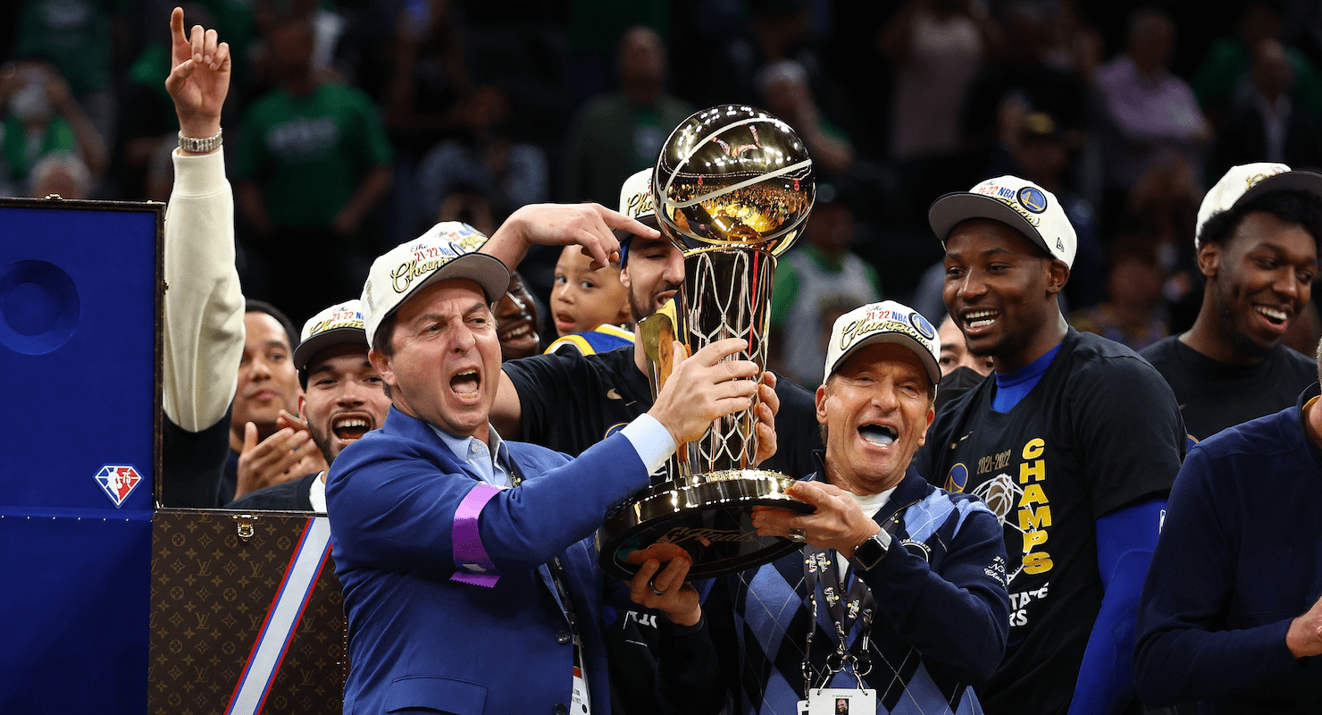 Warriors owners Joe Lacob and Peter Guber hoist the Larry O'Brien NBA championship trophy