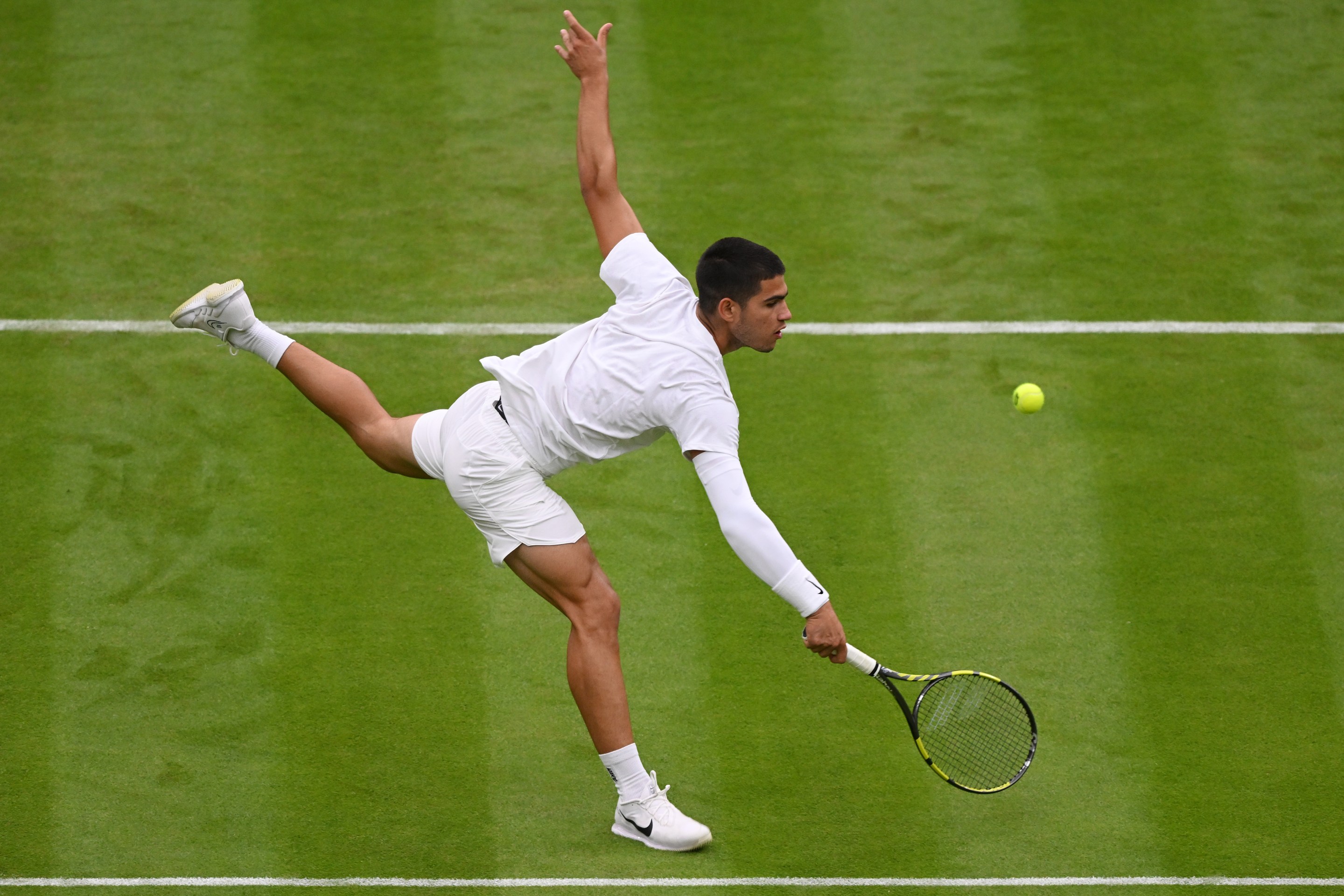 Carlos Alcaraz plays a backhand at Wimbledon.