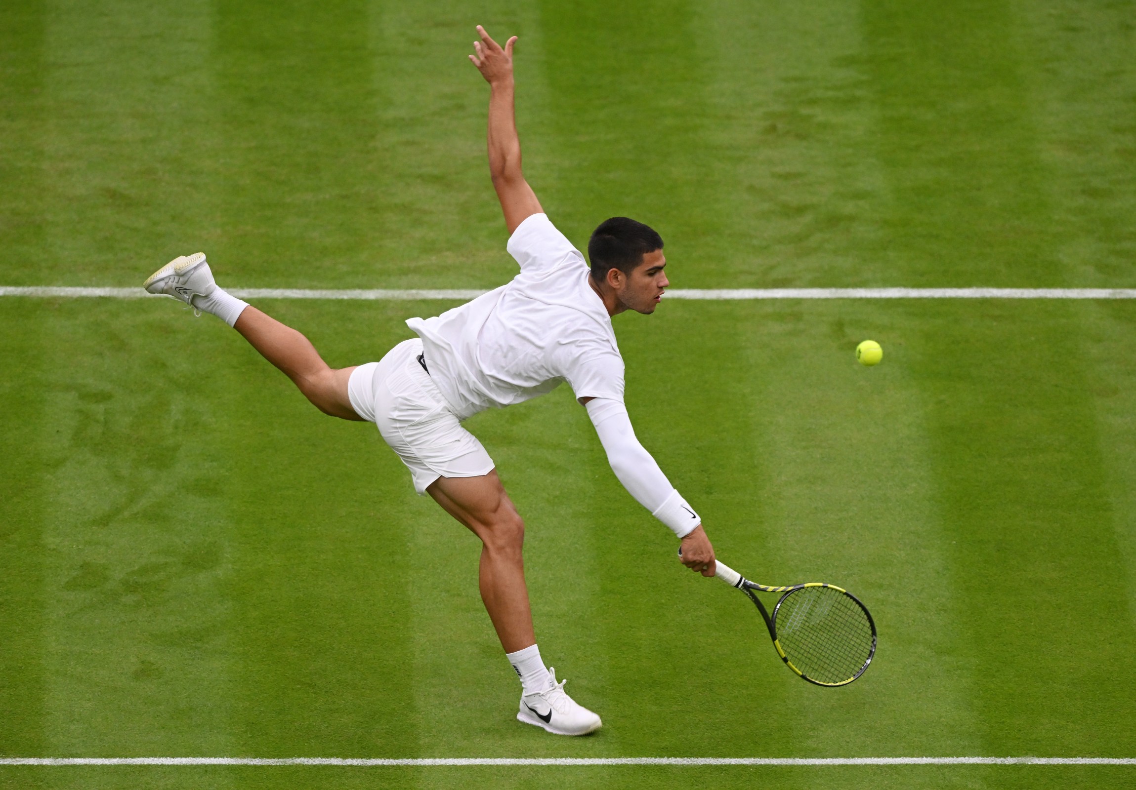 Carlos Alcaraz plays a backhand at Wimbledon.