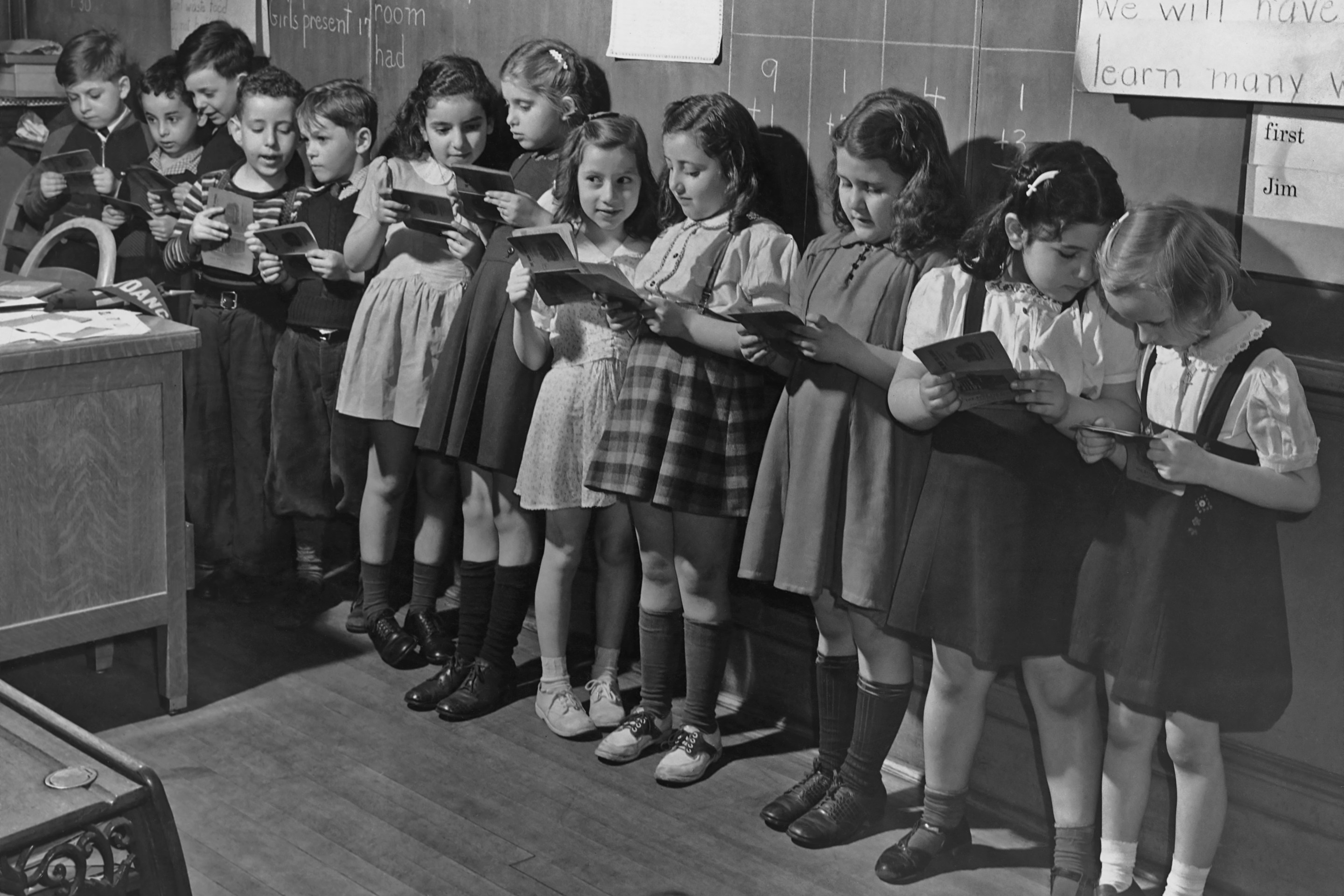 Schoolchildren in a classroom, holding war saving stamp books, USA, circa 1943.
