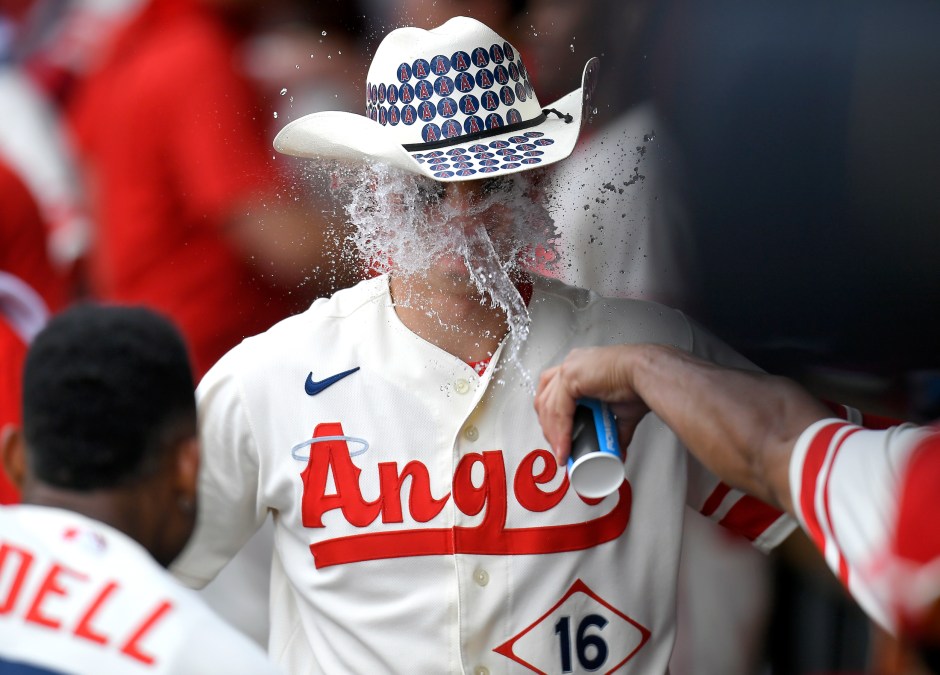Mickey Moniak of the Los Angeles Angels is congratulated for his home run with a cowboy hat and cup of water to the face in the ninth inning against the Oakland Athletics