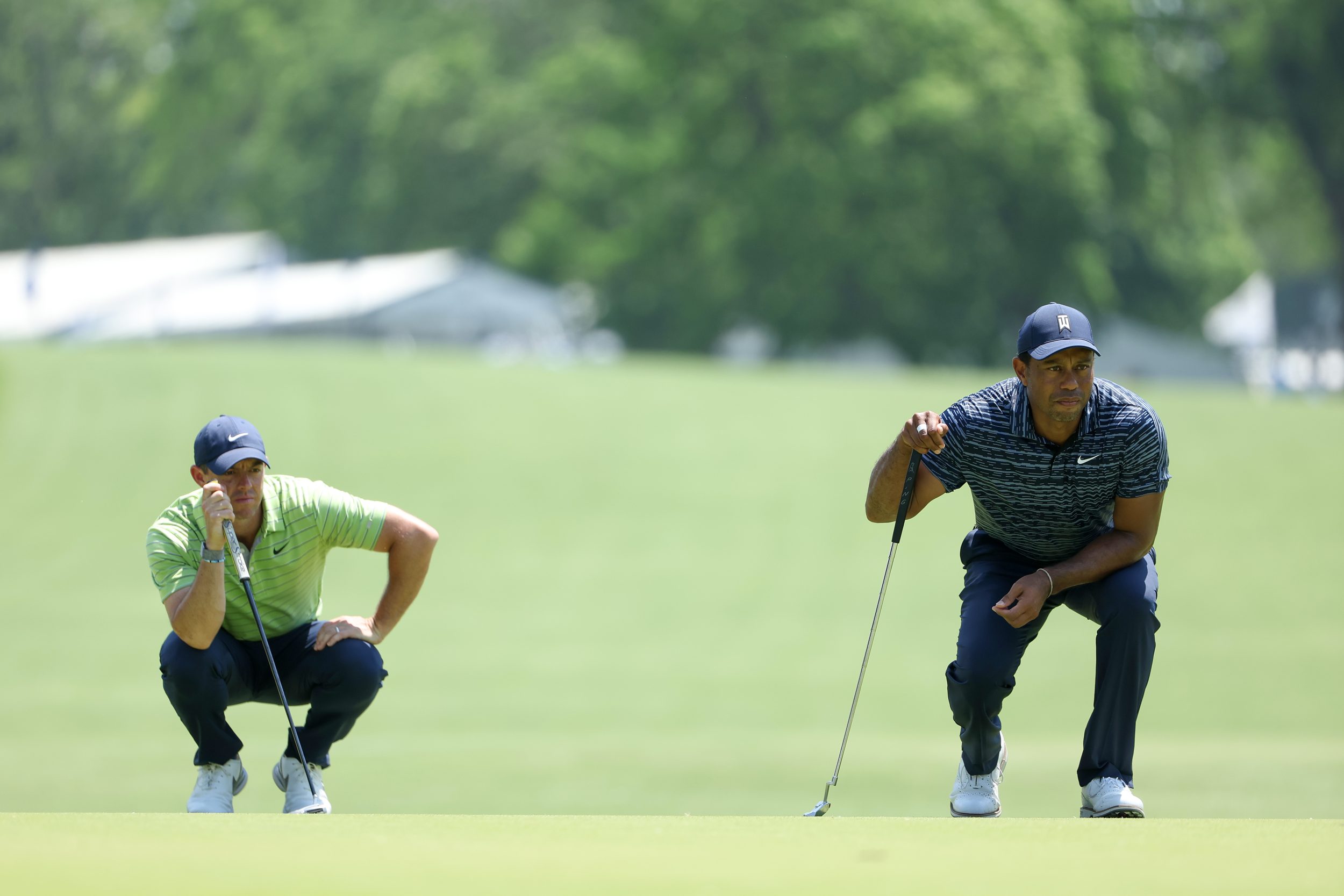 Tiger Woods and Rory McIlroy crouch together.