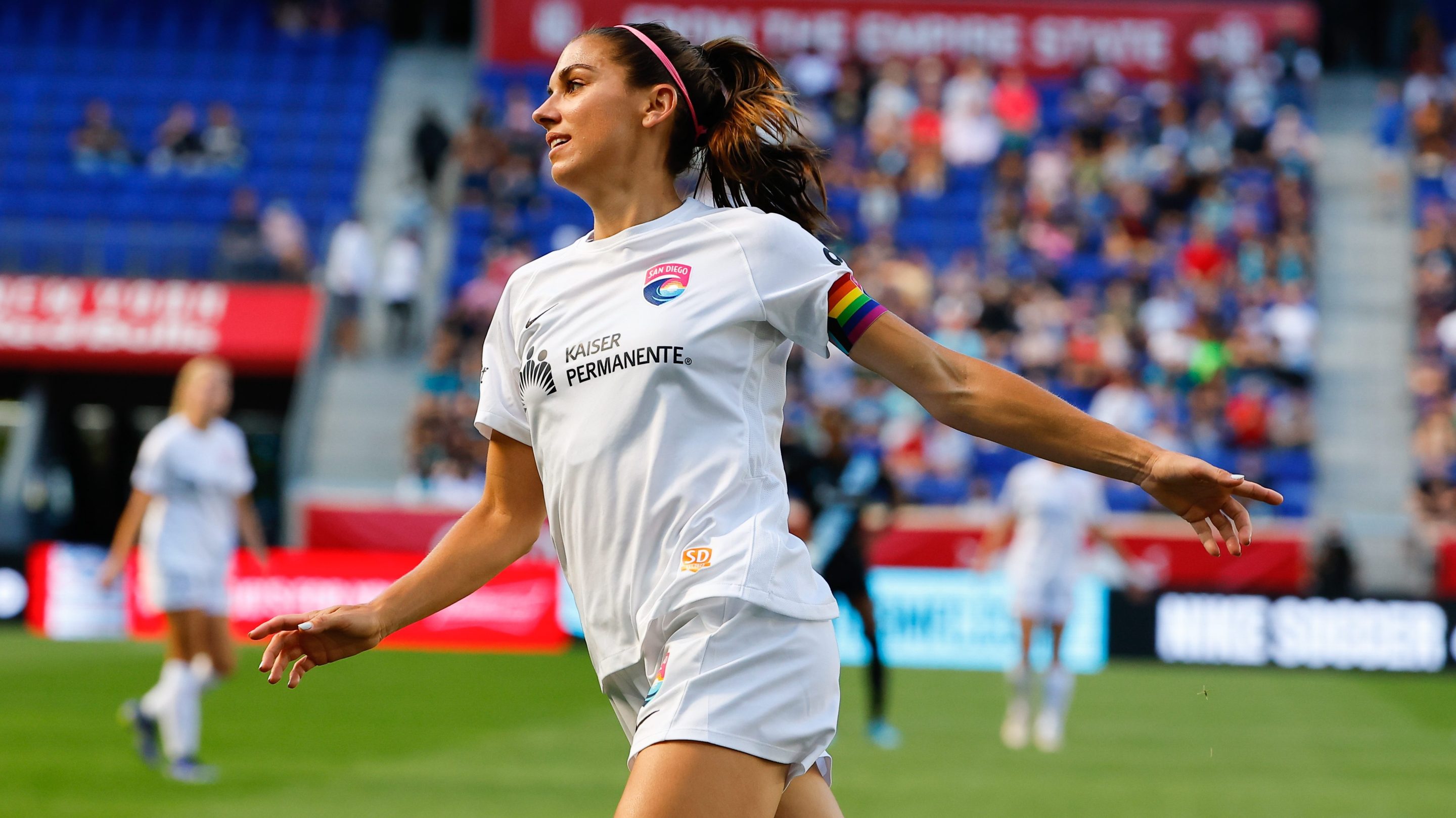 San Diego Wave FC forward Alex Morgan (13) celebrates after scoring during the first half of the NWSL soccer game between NJ/NY Gotham FC and San Diego Wave FC on June 19, 2022 at Red Bull Arena in HArrison, NJ. Her arms are wide open, like an airplane, and she's smiling.