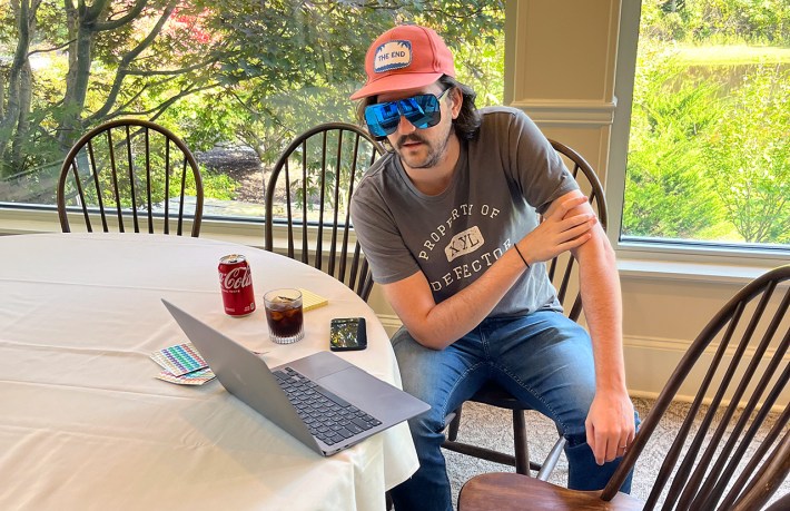 Todd Dipshit, in an orange hat and giant sunglasses, at a laptop