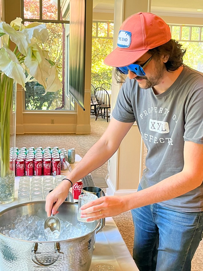 Todd Dipshit, in an orange hat and giant sunglasses, getting some ice