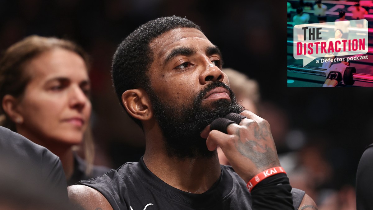 Kyrie Irving on the bench during a Nets game, seemingly staring thoughtfully at The Distraction logo, as if trying to determine its haplogroup.