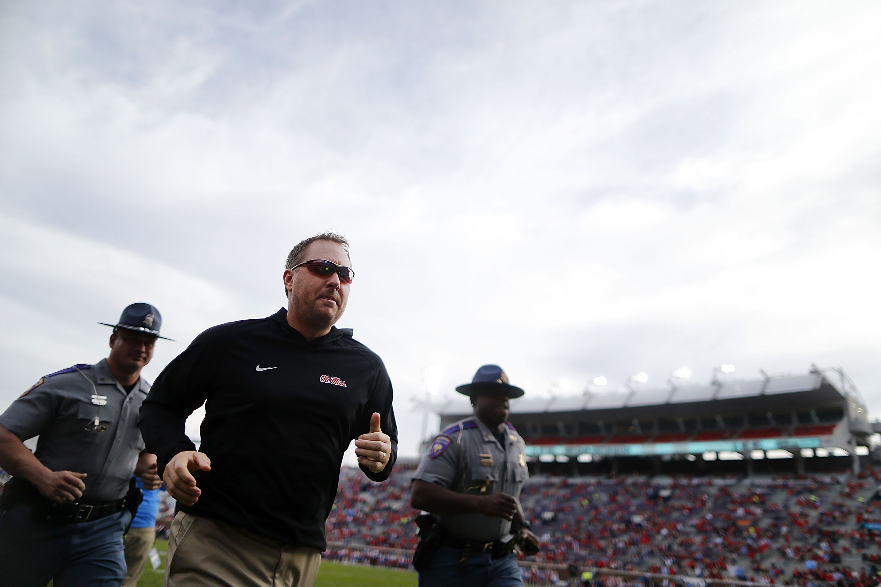 Hugh Freeze runs off the field, accompanied by Mississippi State Troopers, after a home win against Georgia Southern in 2016.