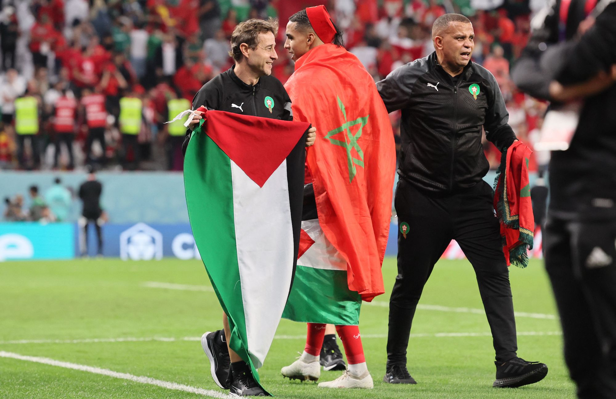 A member of Morocco's team holds a Palestinian flag after the team won the penalty shoot-out to win the Qatar 2022 World Cup round of 16 football match between Morocco and Spain at the Education City Stadium in Al-Rayyan, west of Doha on December 6, 2022.