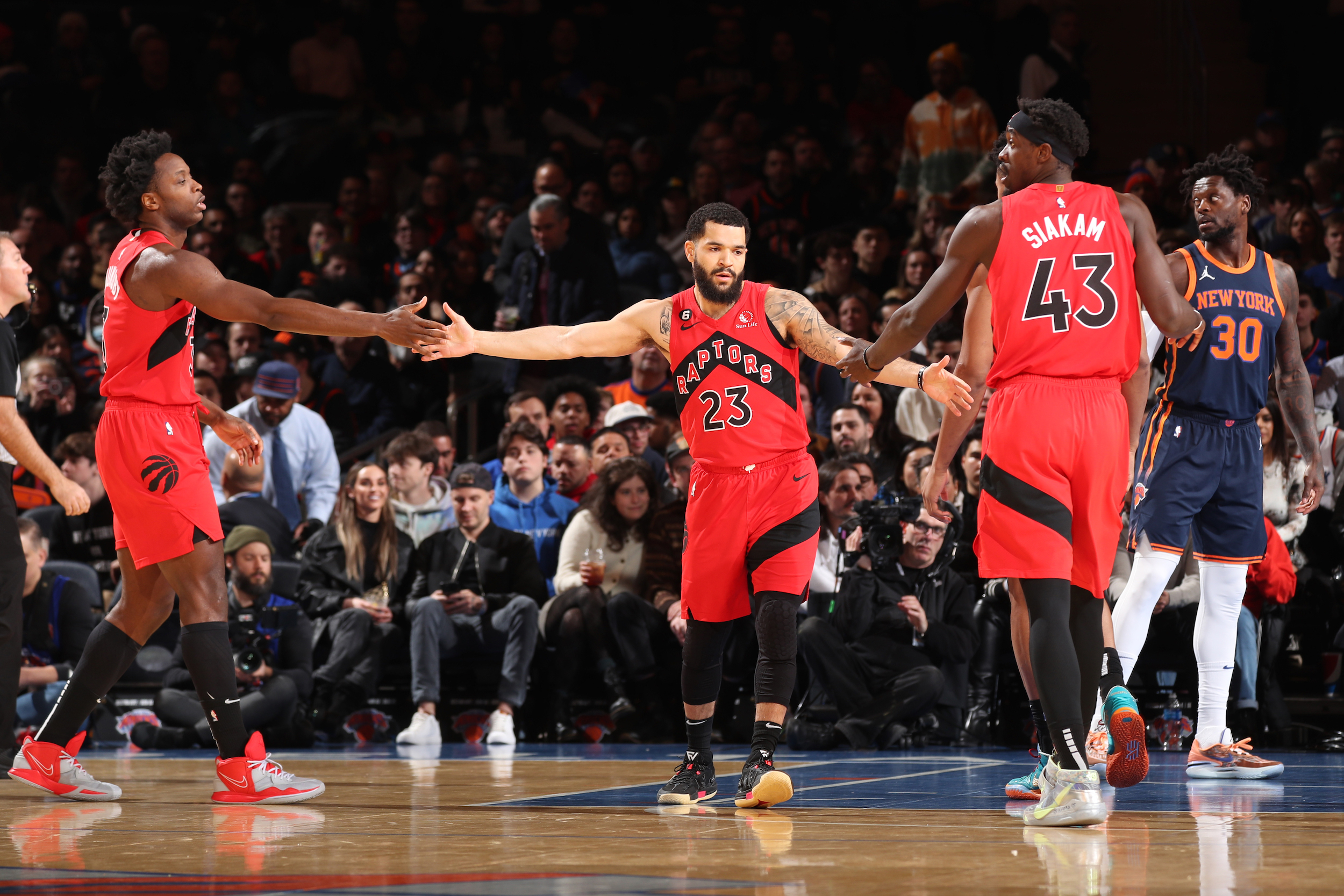 Pascal Siakam, Fred VanVleet, and OG Anunoby exchange high-fives.