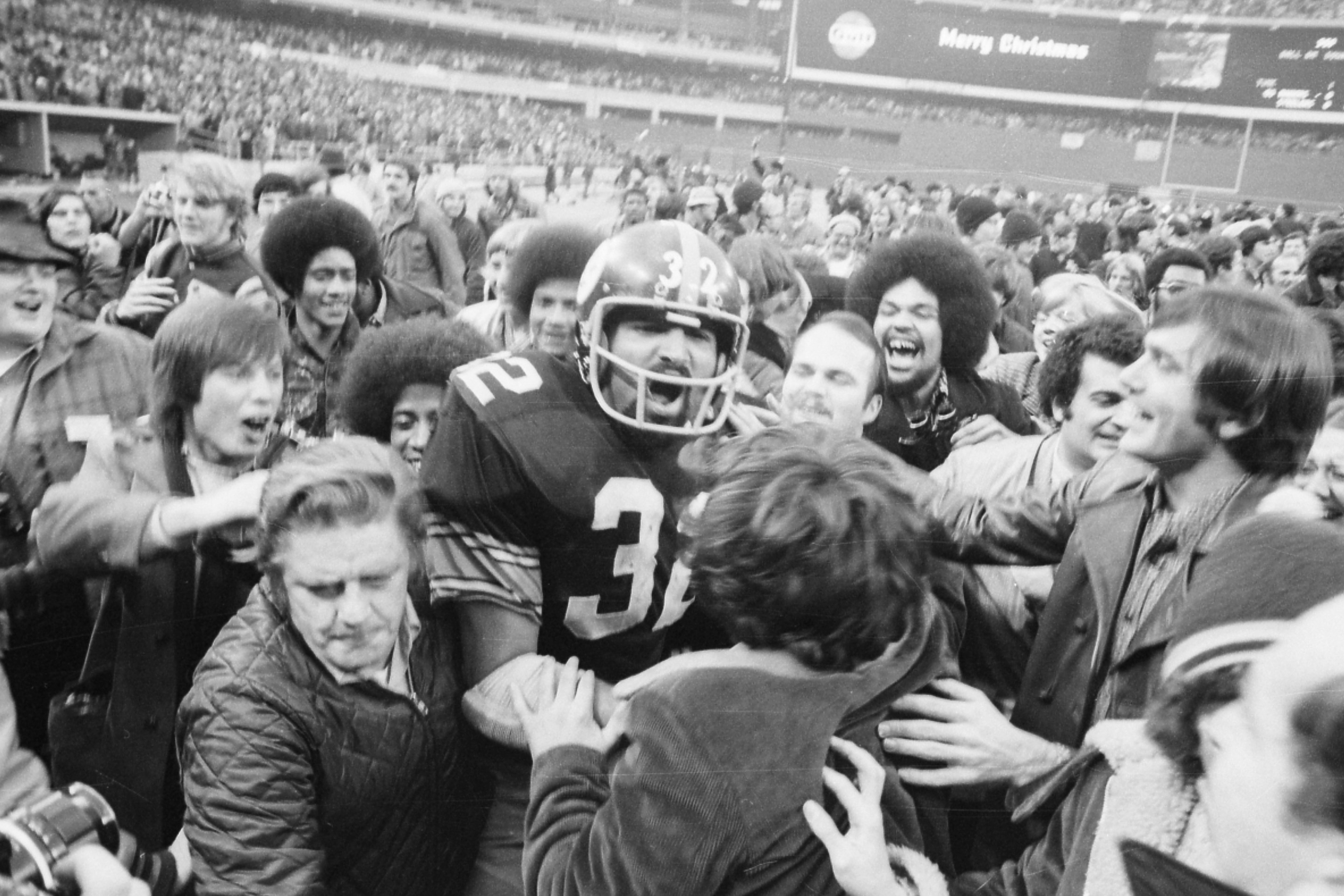 Pittsburgh Steelers' running back Franco Harris is mobed by fans at Three Rivers Stadium after scoring the winning touchdown, nicknamed the "Immaculate Reception," during the American Football Conference (AFC) semi-final game against Oakland. Harris made the touchdown, one of the most famous single plays in the history of professional American football, on a tipped pass from quarterback Terry Bradshaw to Frenchy Fuqua to Harris for the score in the fourth quarter in Pittsburgh.